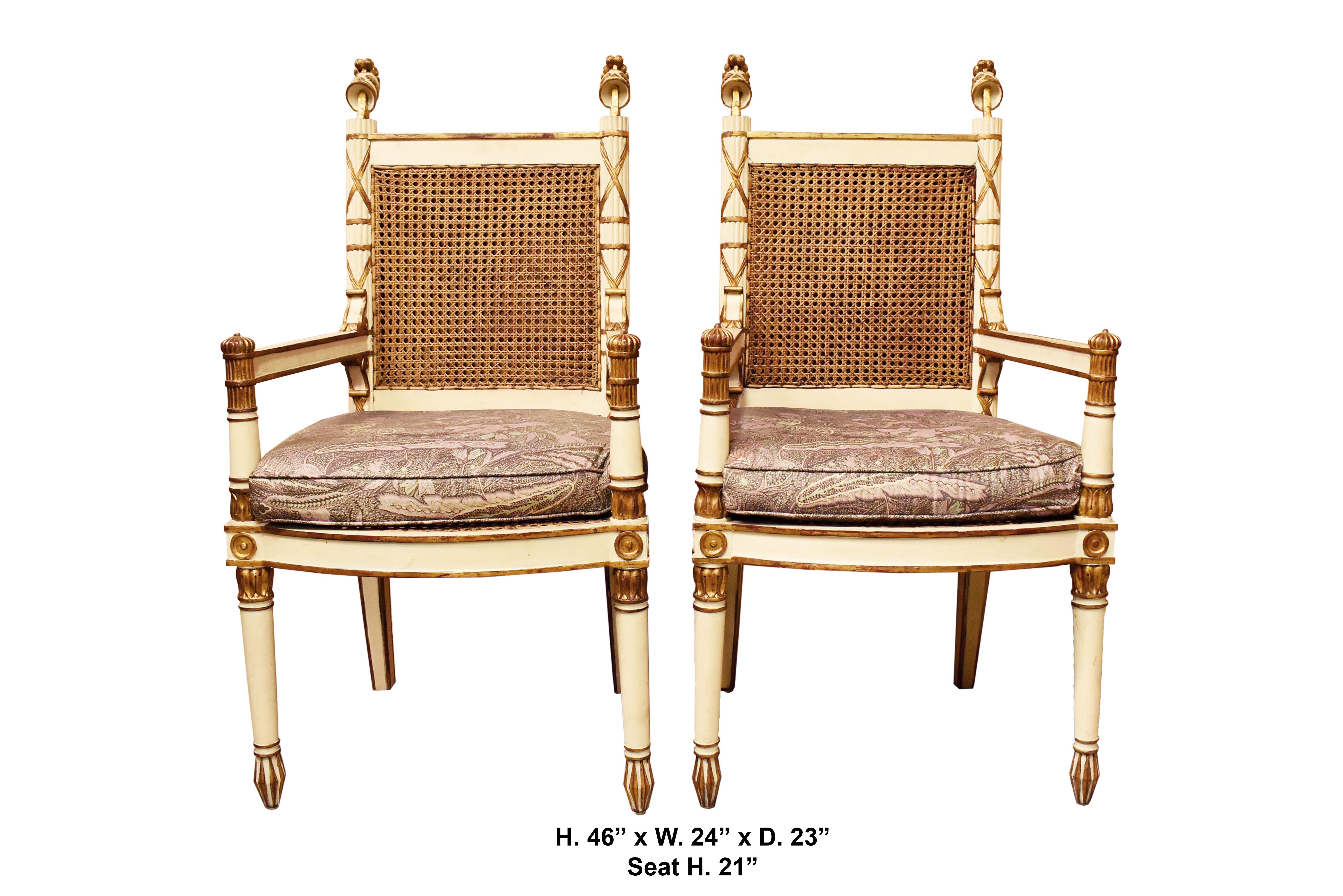 Unique and elegant pair of Italian neoclassical parcel gilt and paint decorated armchairs with cane back and seat with two usable cushions. 
Late 19th-early 20th century 
The back upright stiles are fluted surmounted by a carved galea resting on