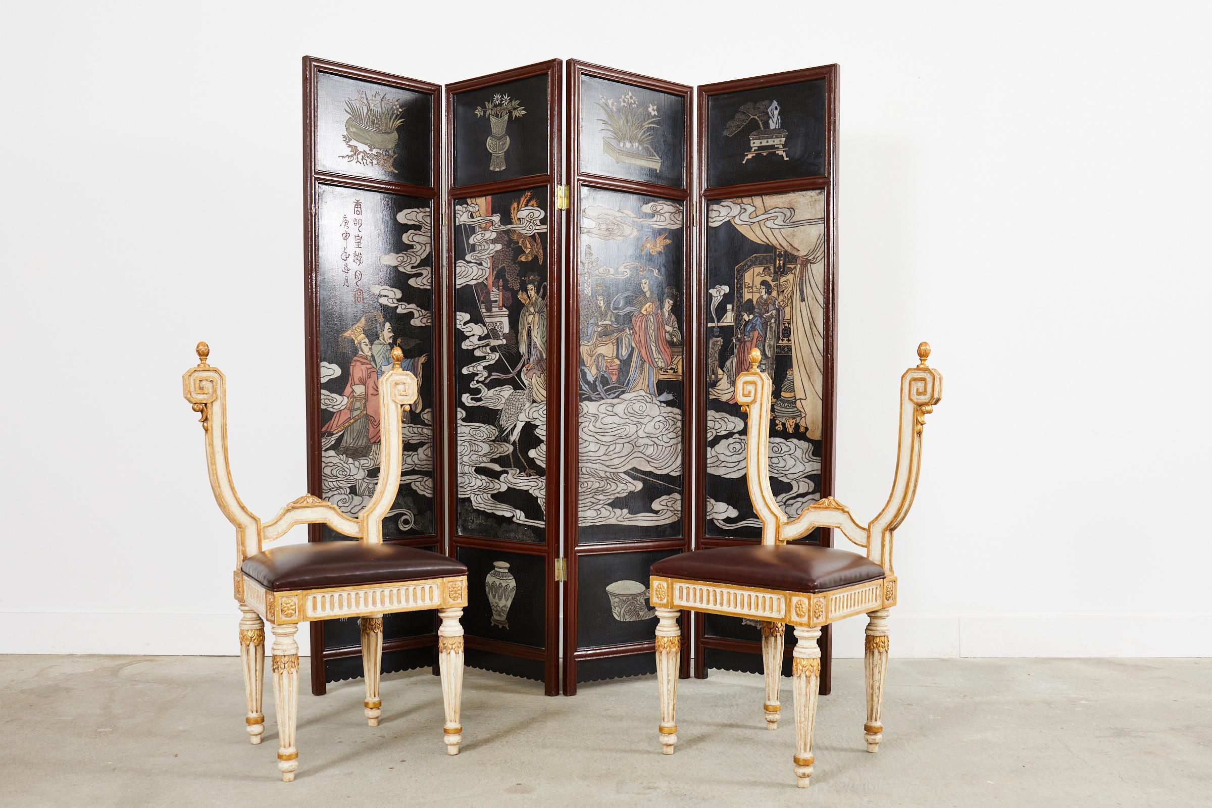 Opulent pair of Italian hall chairs made in the neoclassical style. The chairs feature a backless design having decorative molded raised arms ending with large greek keys topped with finials. The frames have an intentionally aged, distressed lacquer