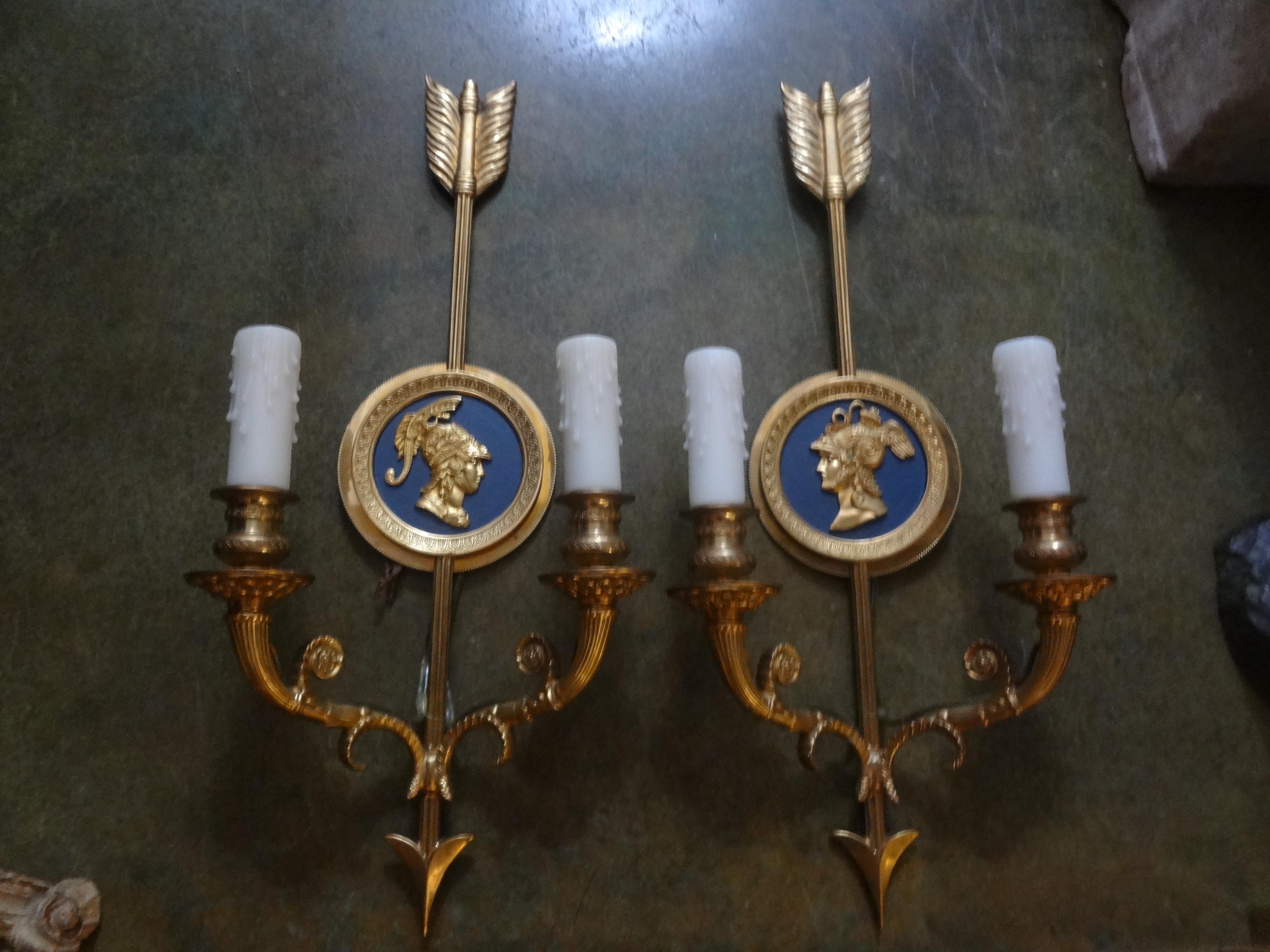 Fabulous pair of Italian Maison Jansen style, neoclassical or Empire style two-light brass sconces with arrows and opposing center medallion figures. This stunning pair of Italian neoclassic beautifully chased brass sconces are marked Italy on the