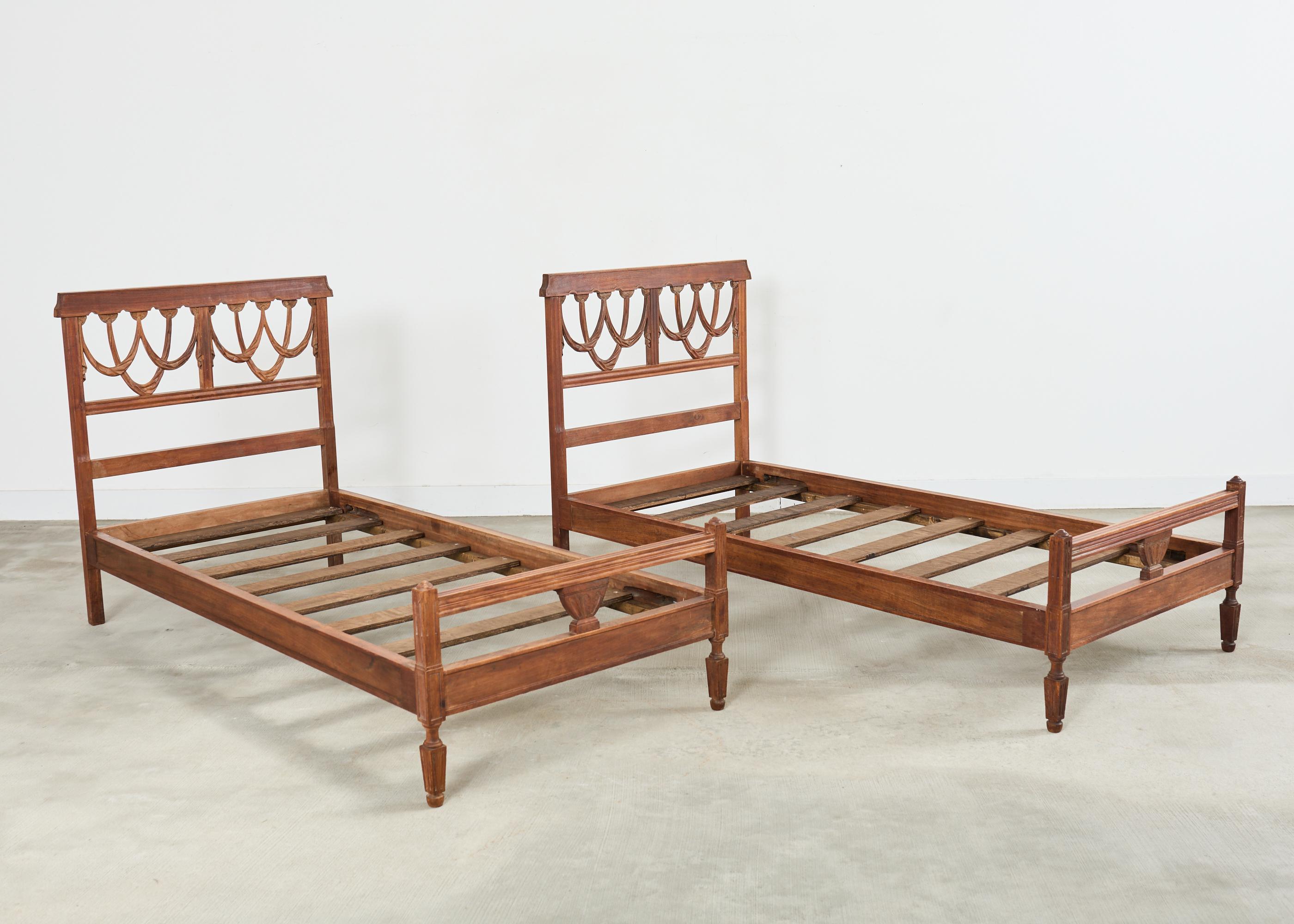 Paire de cadres de lit italiens sculptés du XIXe siècle, avec têtes de lit en trompe-l'Oeil de style néoclassique. La finition du bois de hêtre massif présente une patine vieillie par les intempéries qui met en valeur le caractère naturel du bois.