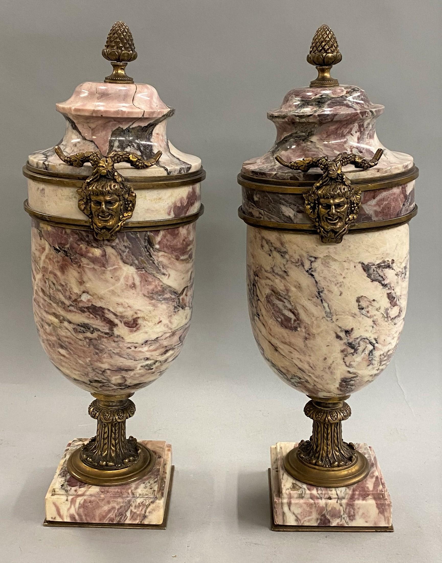 A fine pair of Italian Neoclassical style marble urns, with bronze mounts  including bronze heads of Satyr or Faun the sides of each urn, bronze bud finials, and a bronze acanthus decorated stem, supported by a square marble base on a bronze plate.