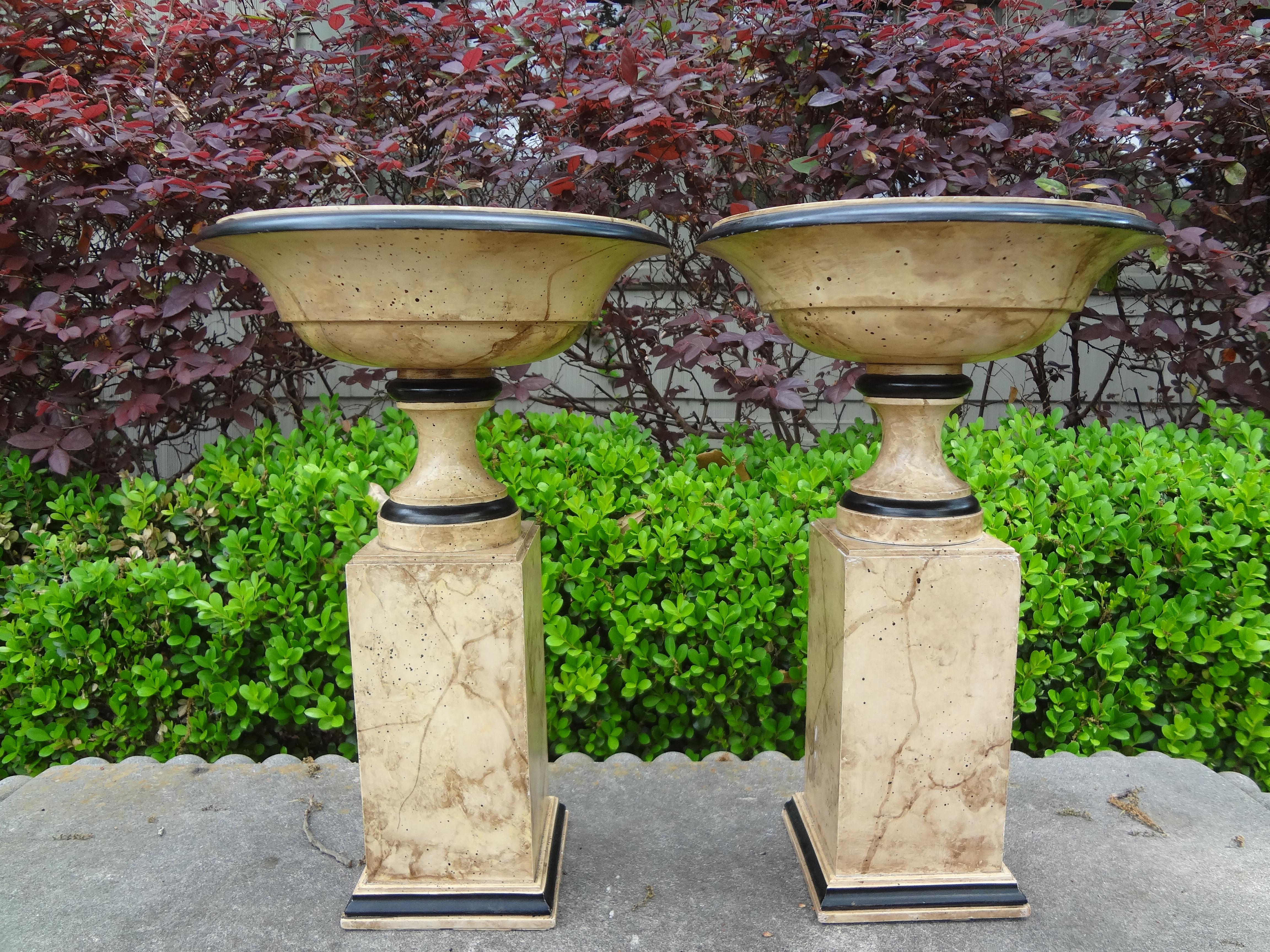 Stunning pair of Italian neoclassical style marbleized carved wood tazza urns. This beautiful pair of Italian urns or garniture are sitting on marbleized plinths and would look great on a mantle, dining table, cocktail table or in a bookcase.