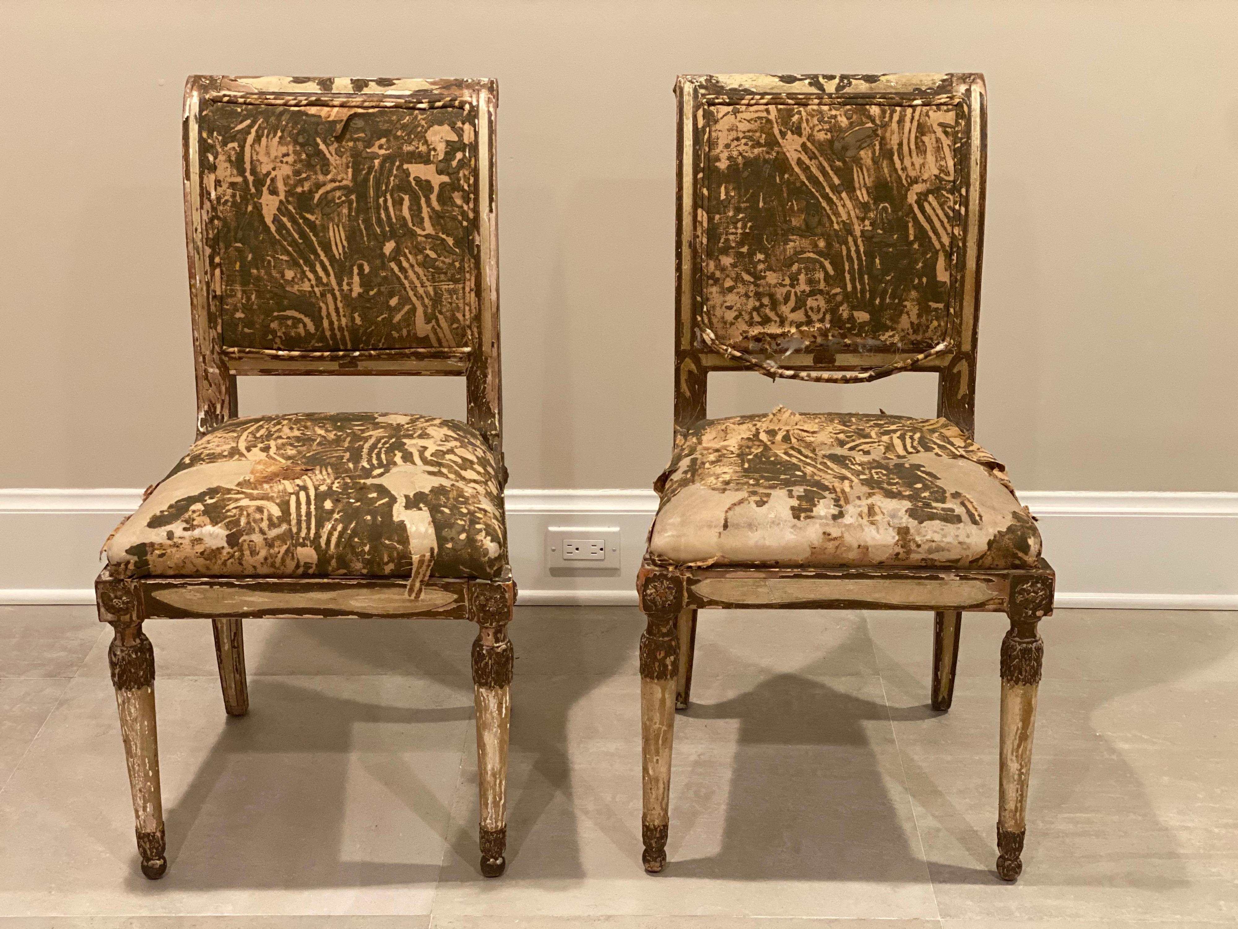 Pair of Italian neoclassical gilt side chairs in painted and gilt finish with remnants of fabric still showing.
The chairs have a lovely scrolled back and splayed back legs. Front legs round and taper. Both chairs are in good stable condition
