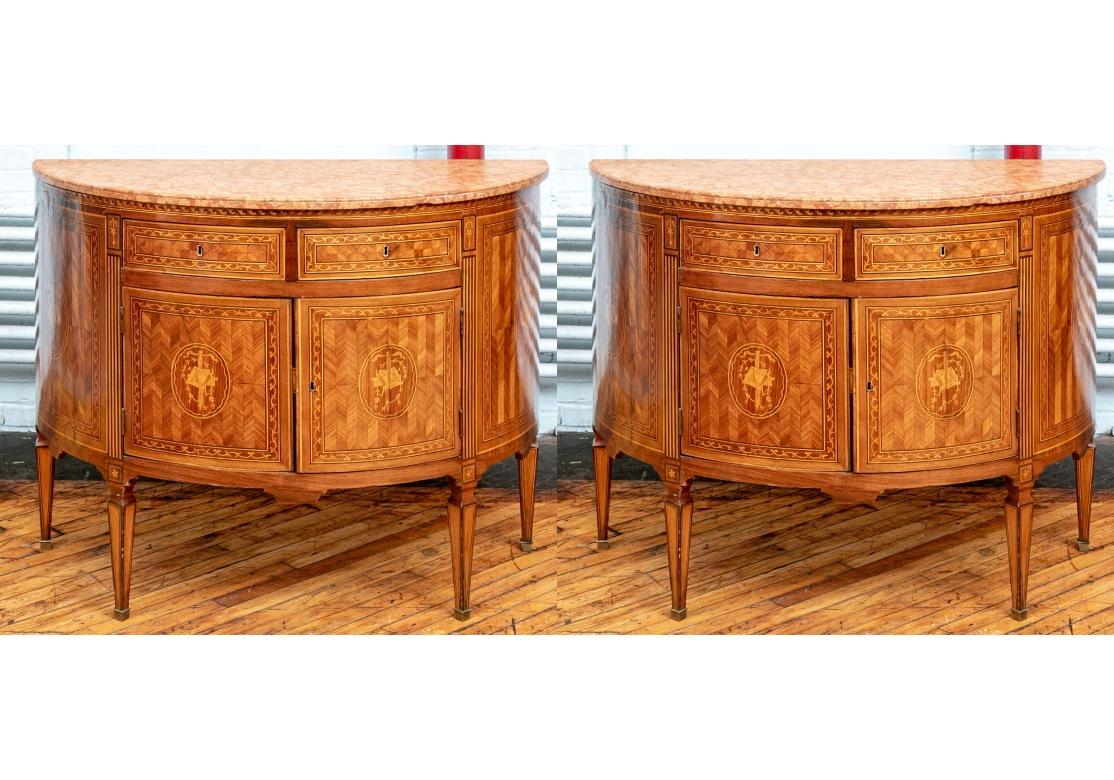 Finely crafted pair of bow front chests with  pink marble conforming tops. The fronts with two apron drawers in herringbone parquetry with marquetry foliate framing bands.  The lower double doors with conforming parquetry and marquetry, along with