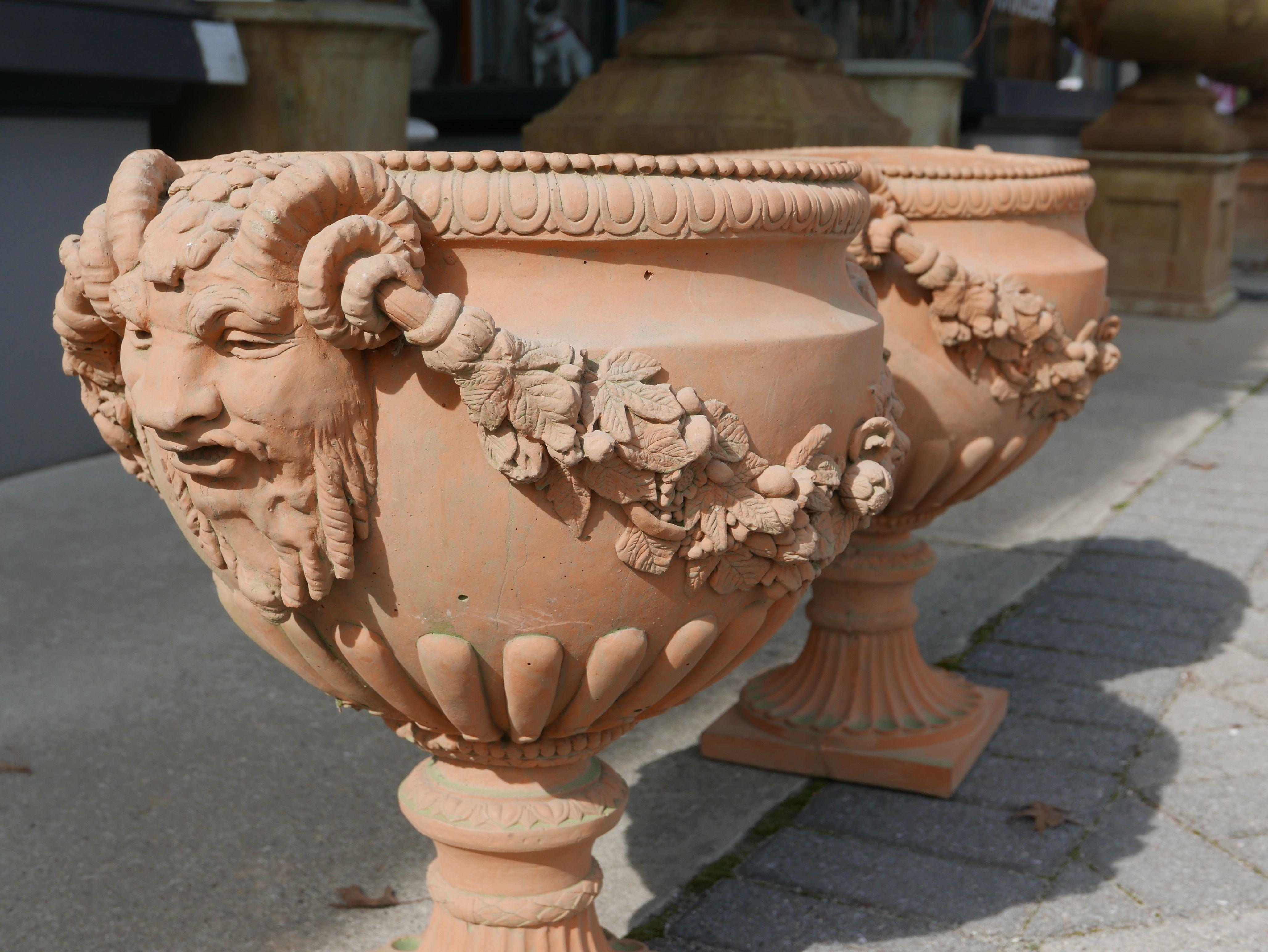 This pair of neoclassical style terracotta jardinières were produced in Italy during the 1920s-1930s. Each come as a classical formed gadrooned urn, with rope motif and egg-and-dart border to rim, over intricately detailed floral festoons, flanked