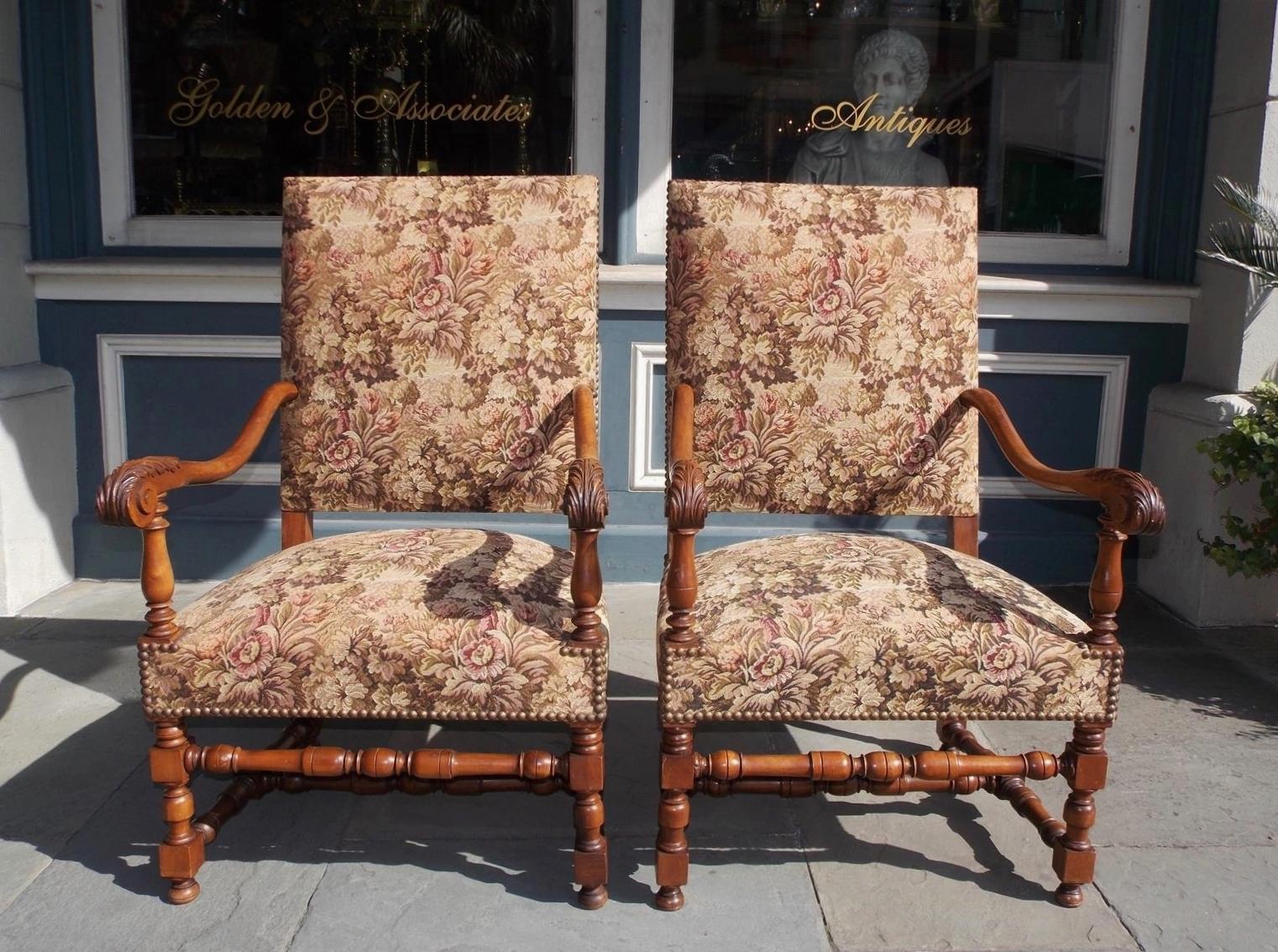 Pair of Italian neoclassical walnut arm chairs with upholstered squared backs, flanking scrolled acanthus arms, upholstered seats with brass tacks, and terminating on turned bulbous ringed blocked legs with the original connecting stretchers,