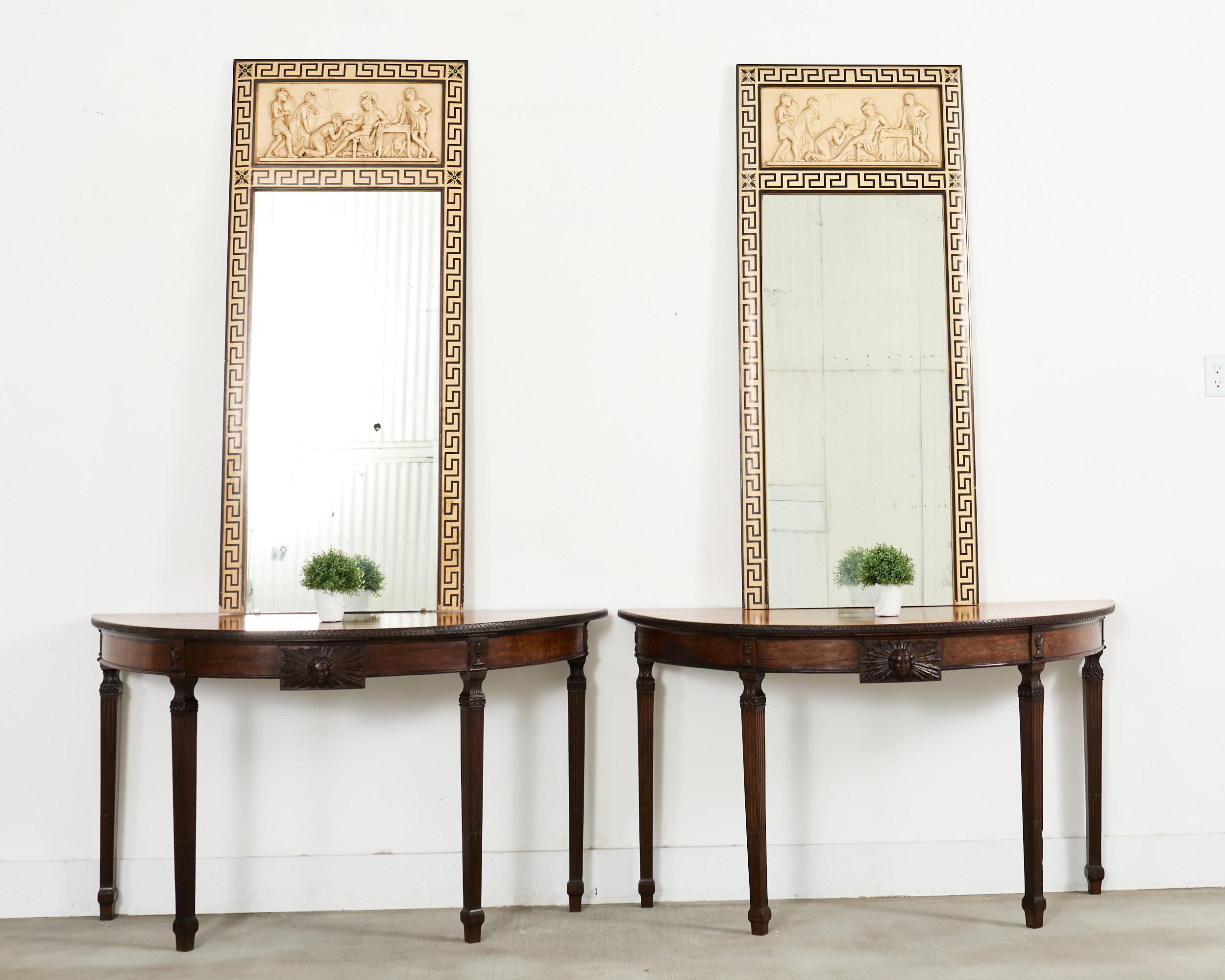 Phenomenal pair of 18th century Italian demi-lune console tables featuring neoclassical Greco-Roman plaques having an Apollo bust with a radiating sunburst mounted to the frieze. The console tables are crafted from walnut with rich woodgrain