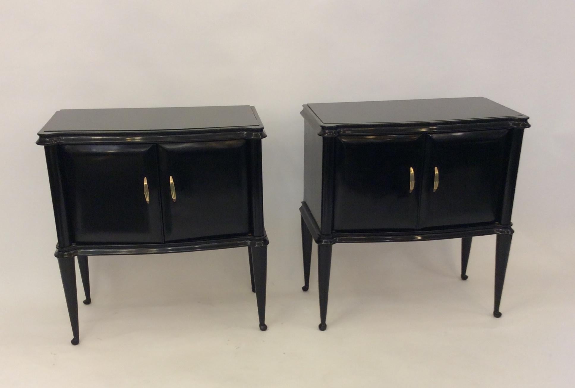 Pair of nightstands/ side tables in ebonized wood with brass hardware and black glass top.