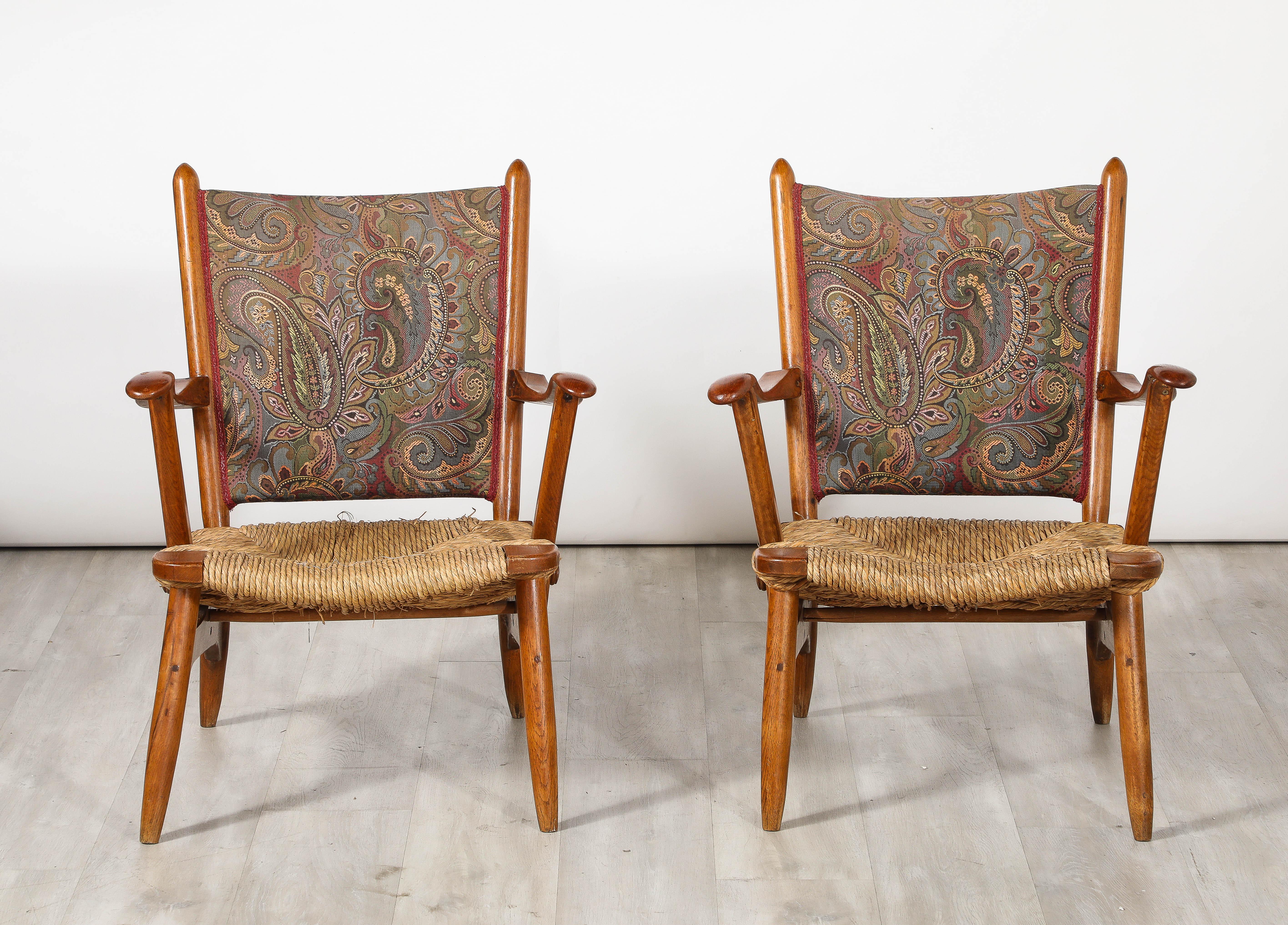 A pair of wonderfully organic Dutch armchairs in walnut with hand-woven rush seats and upholstered backs covered with a paisley design.  The form is greatly considered and perfectly executed, the carving is exceptionally sophisticated, making a
