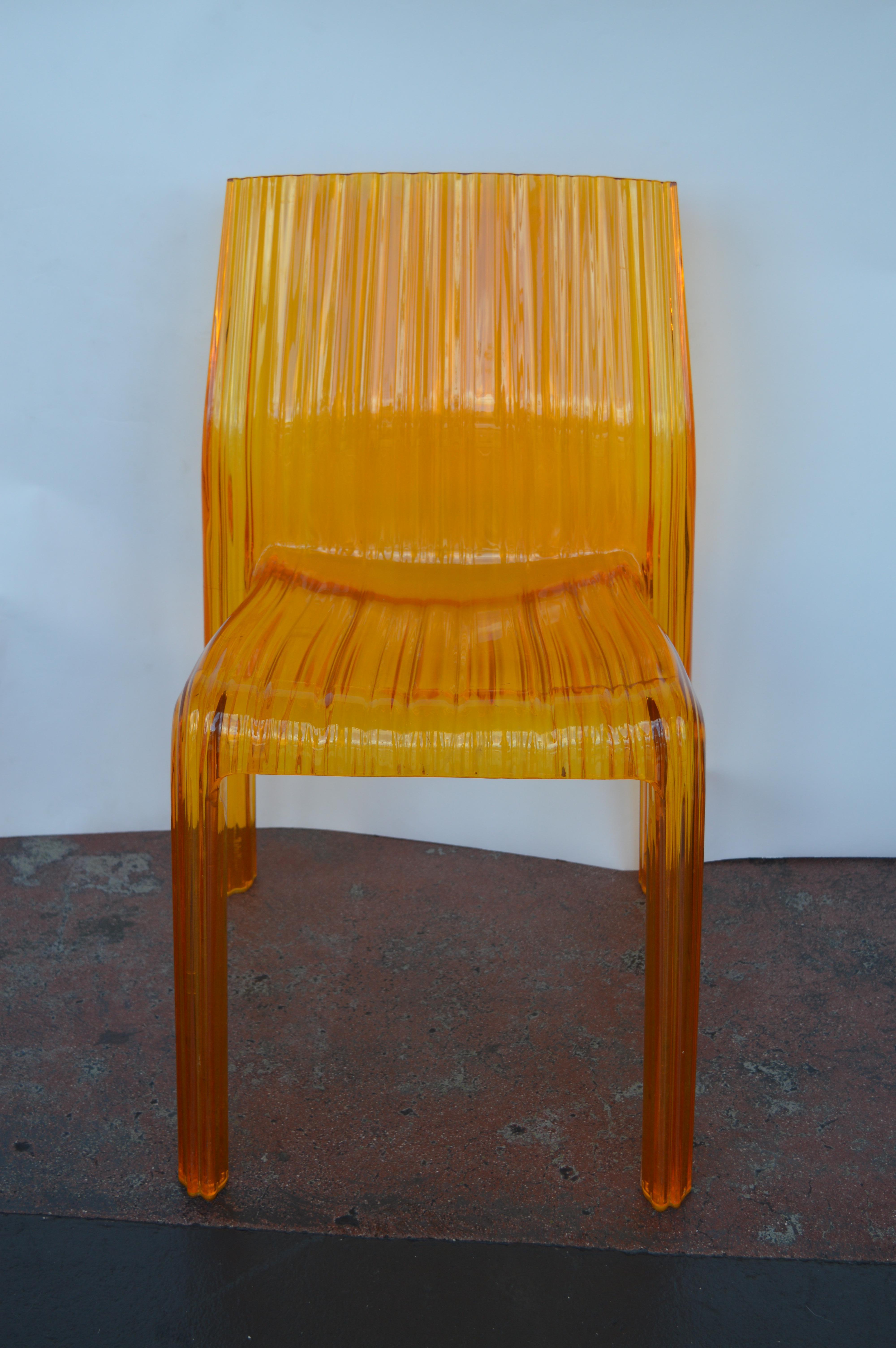 Two orange Lucite chairs by Kartell with the original stamp.