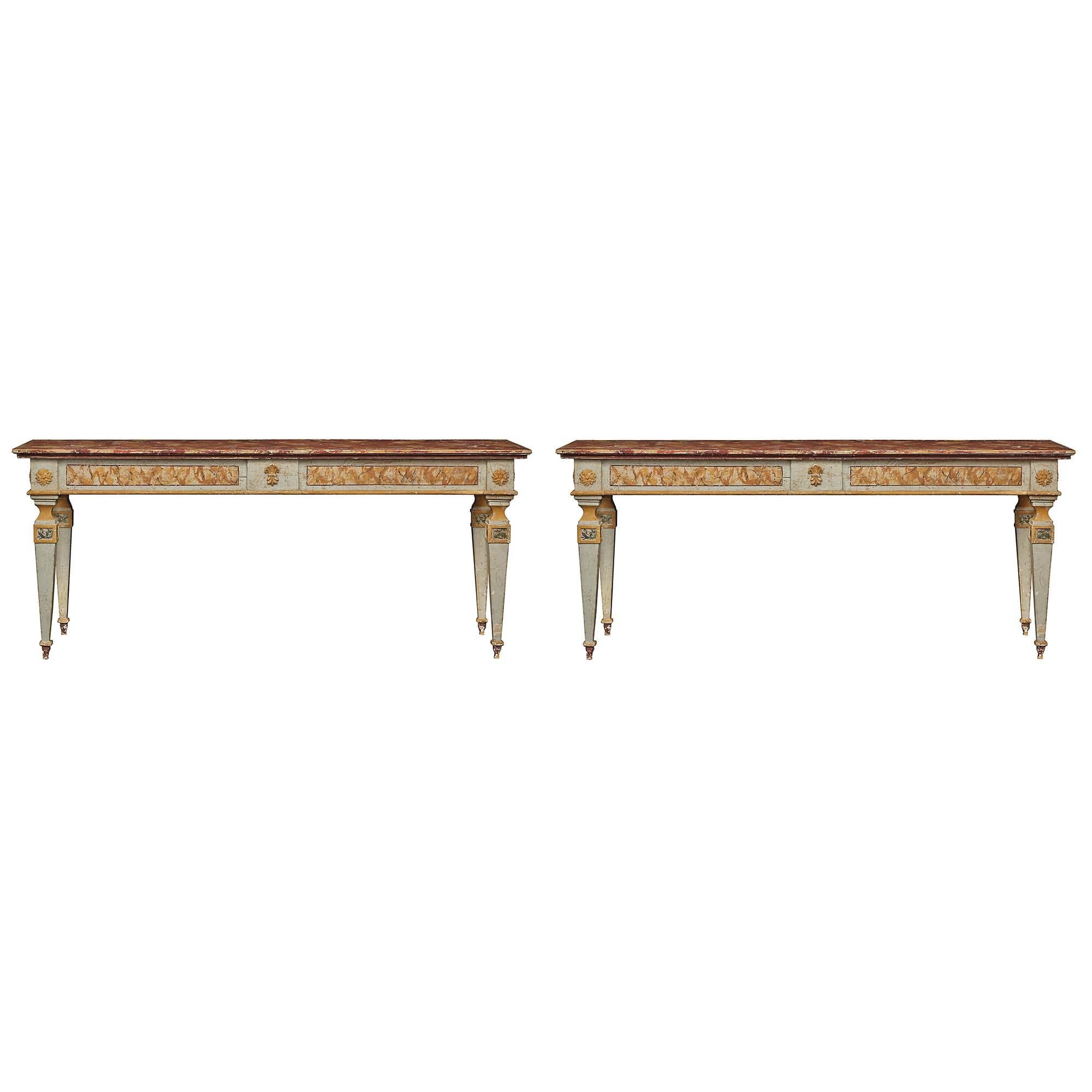 A large pair of Italian painted 19th Century free standing consoles. The pair are raised by four square tapered legs below large yellow carved rosettes. The frieze has two rectangular faux marble designs on both sides of a central Fleur de Lis. The