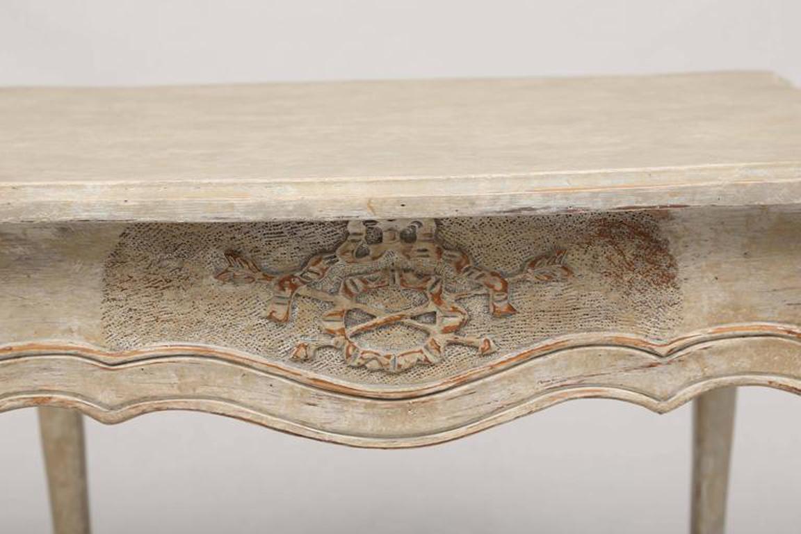 Pair of painted end tables, each having a molded rectangular top, its serpentine apron carved with neoclassical motifs, a single frieze drawer on the narrow side of the table, raised on square-section cabriole legs, turned to the 45-degree angle.