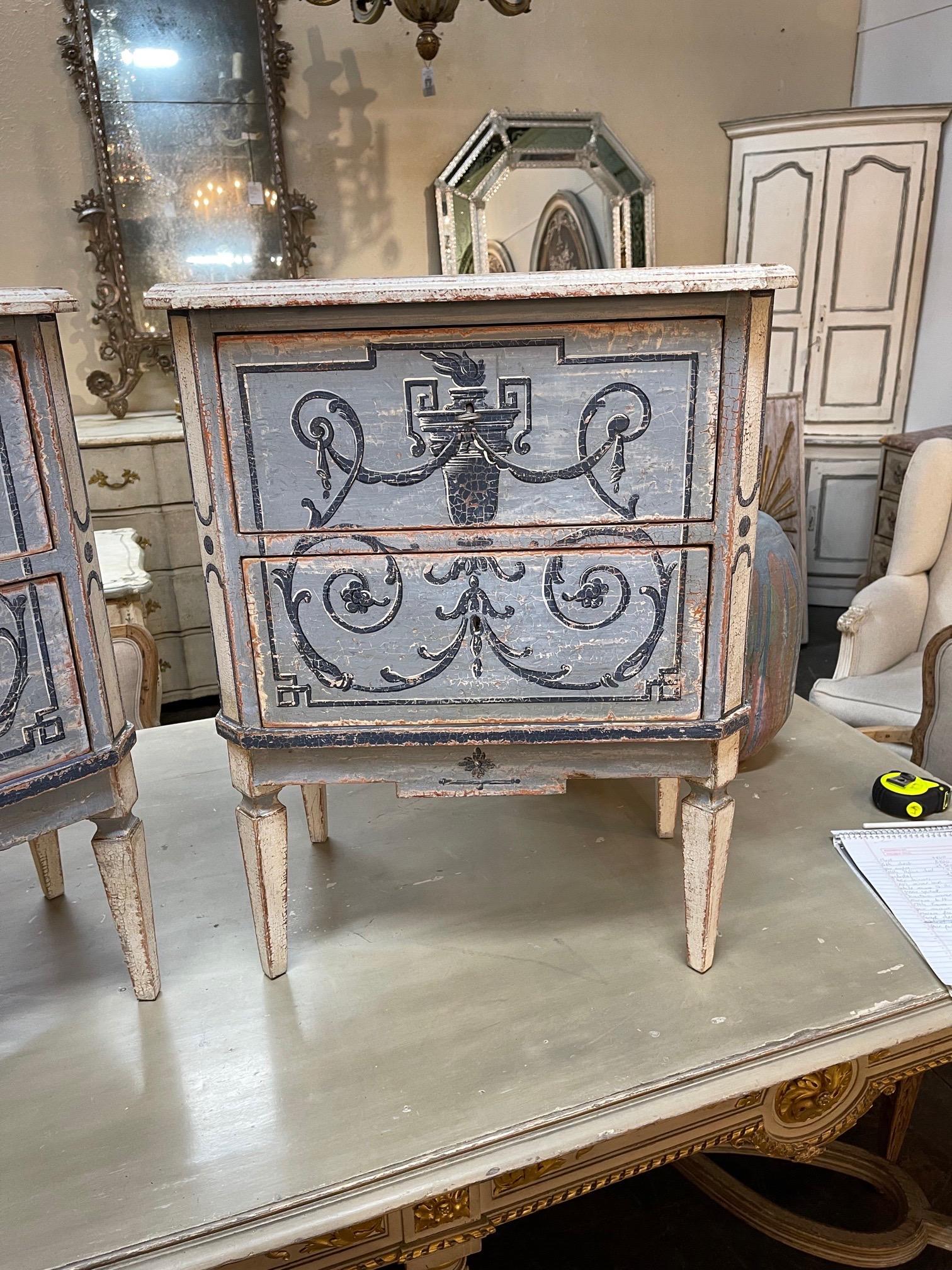 Decorative pair of hand painted Italian Neo-Classical style 2 drawer bed side tables. Nice design featuring an urn and floral images. The piece has lovely colors of blue and white as well. So pretty!!