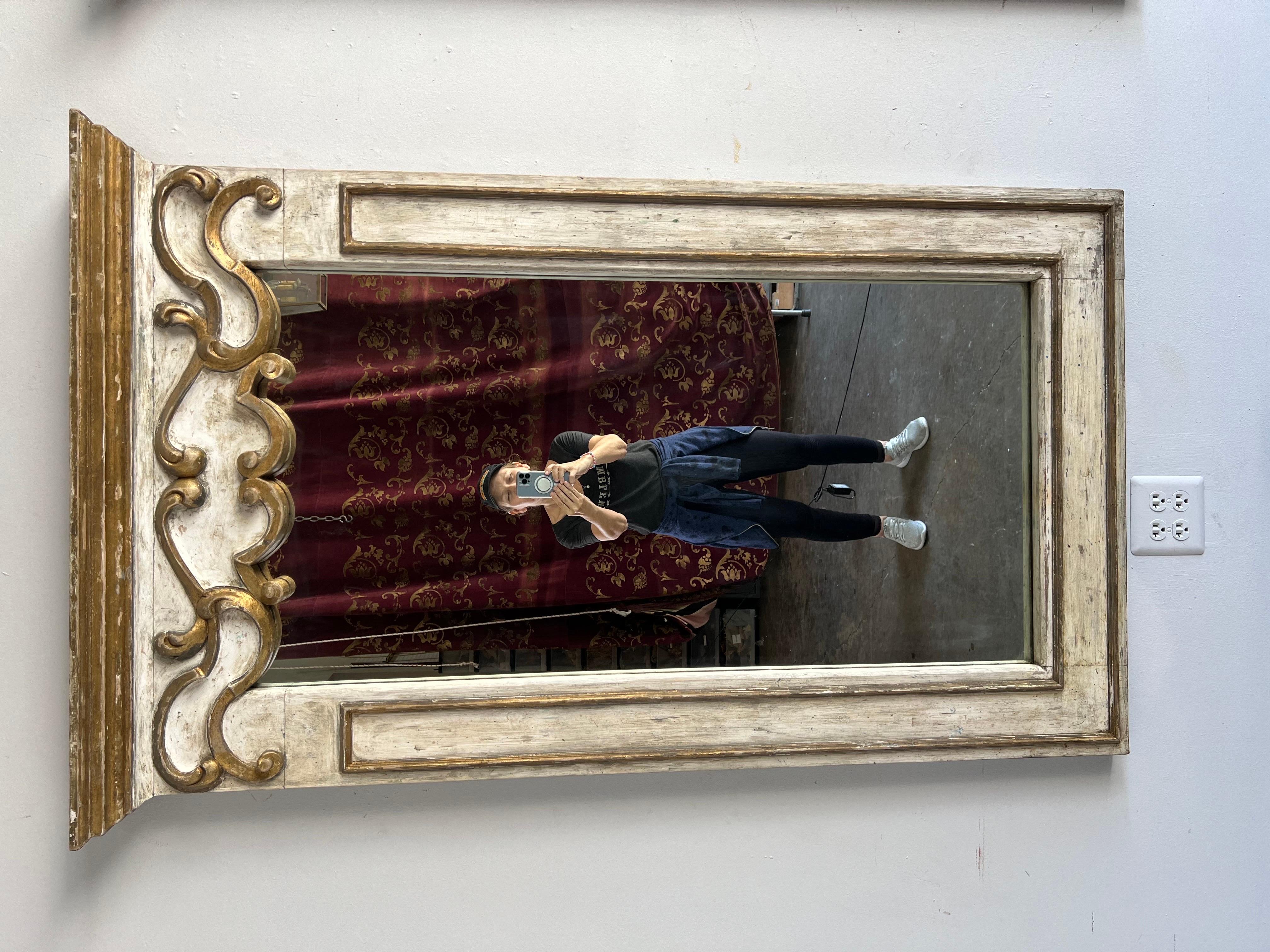 Pair of custom Italian style painted & parcel gilt mirrors originally made by 
Timothy Corrigan. The mirror are painted antique white and have gold leaf on the raised portions of the mirrors. There is missing paint and gold leaf throughout. the pair