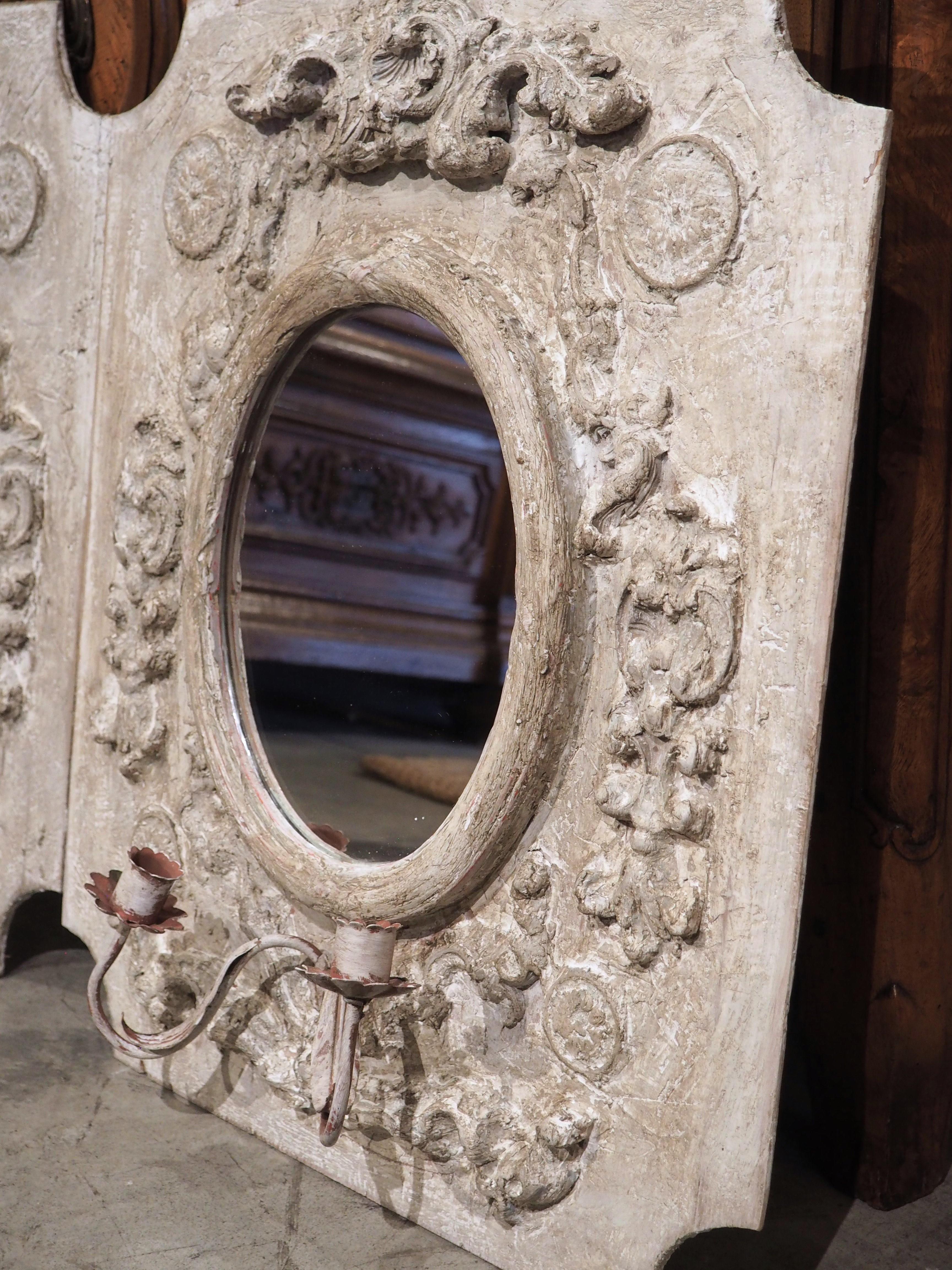These small, painted Italian panels are sure to make a statement in any home. Meticulously hand-crafted in Florence, they feature oval mirrors and iron sconces finished with an antique white patina that gives them character and depth. Ornamentation