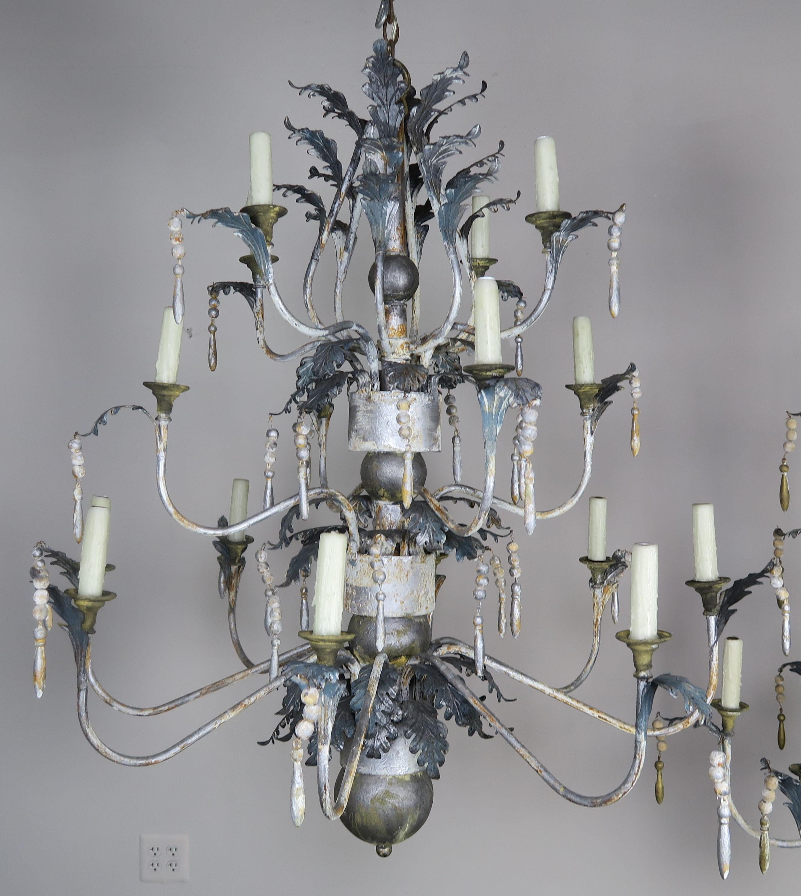 Pair of Italian painted wood and metal chandeliers with acanthus leaves and wood tassels throughout. Newly rewired and in working condition with chain and canopy included.