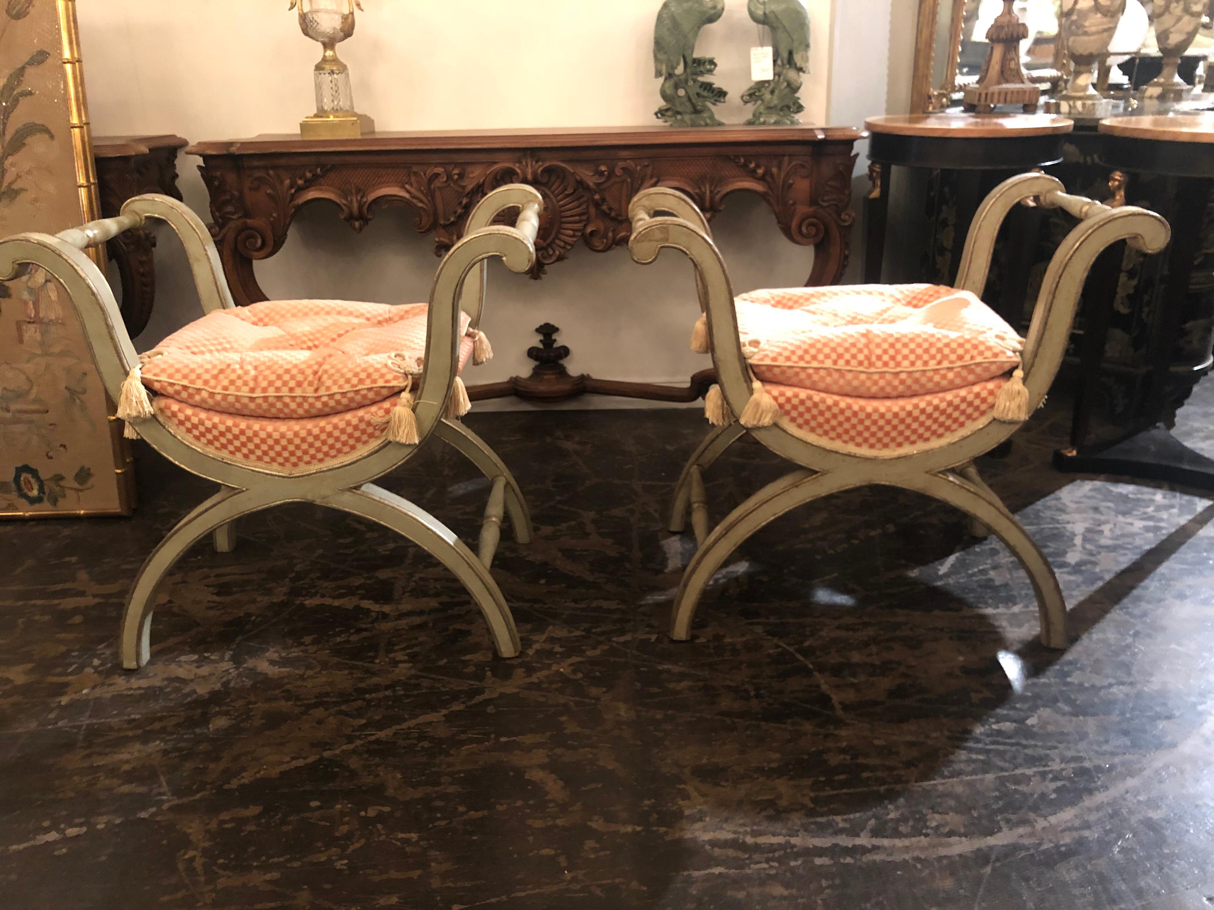 Very nice pair of X Form Benches painted in a nice silver grey patina with gold highlights.
Lovely upholstered cushions in a crème and peach colored fabric.
