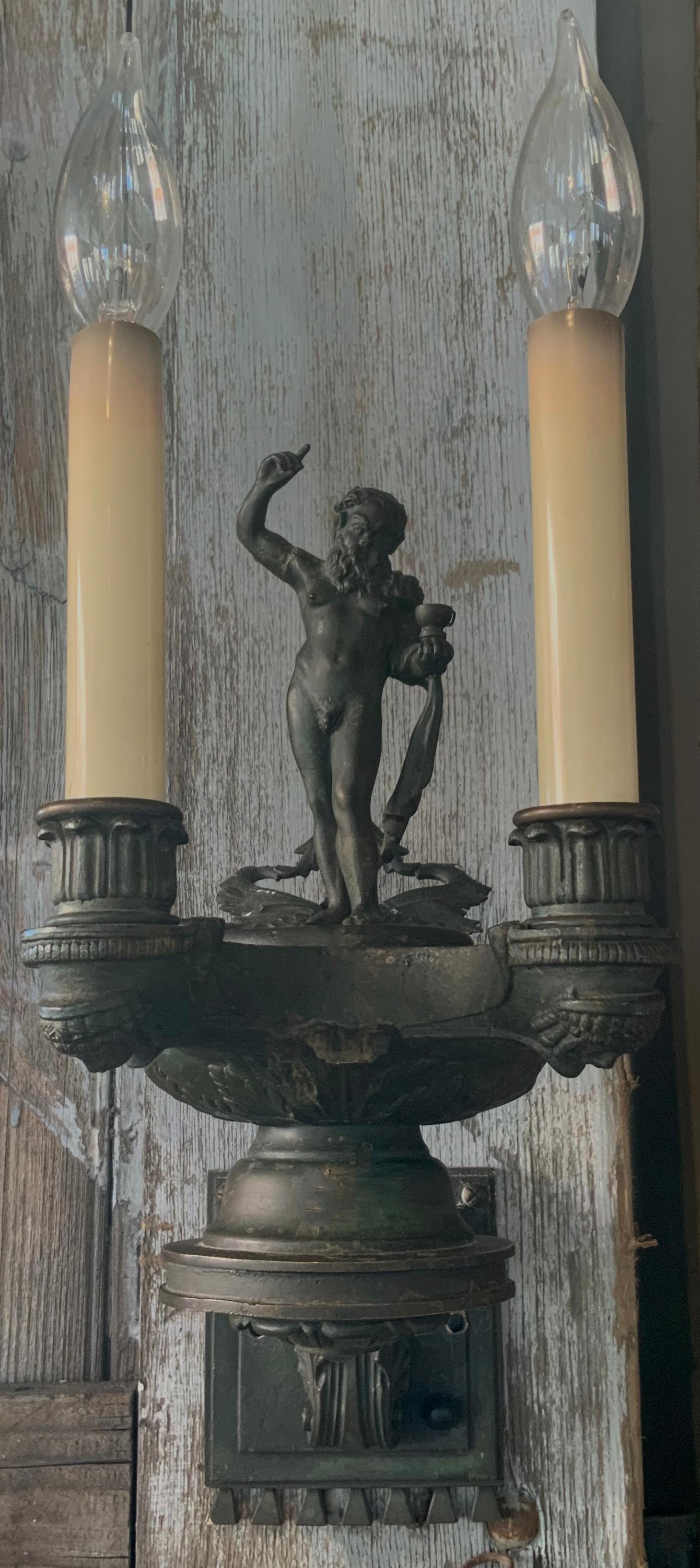 Pair of Italian patinated bronze sconces with the figure of Bacchus. The design is classic Roman in the form of oil lanterns decorated with acanthus leaf and the figure of Bacchus, the God of architecture, wine and fertility as the focus of the