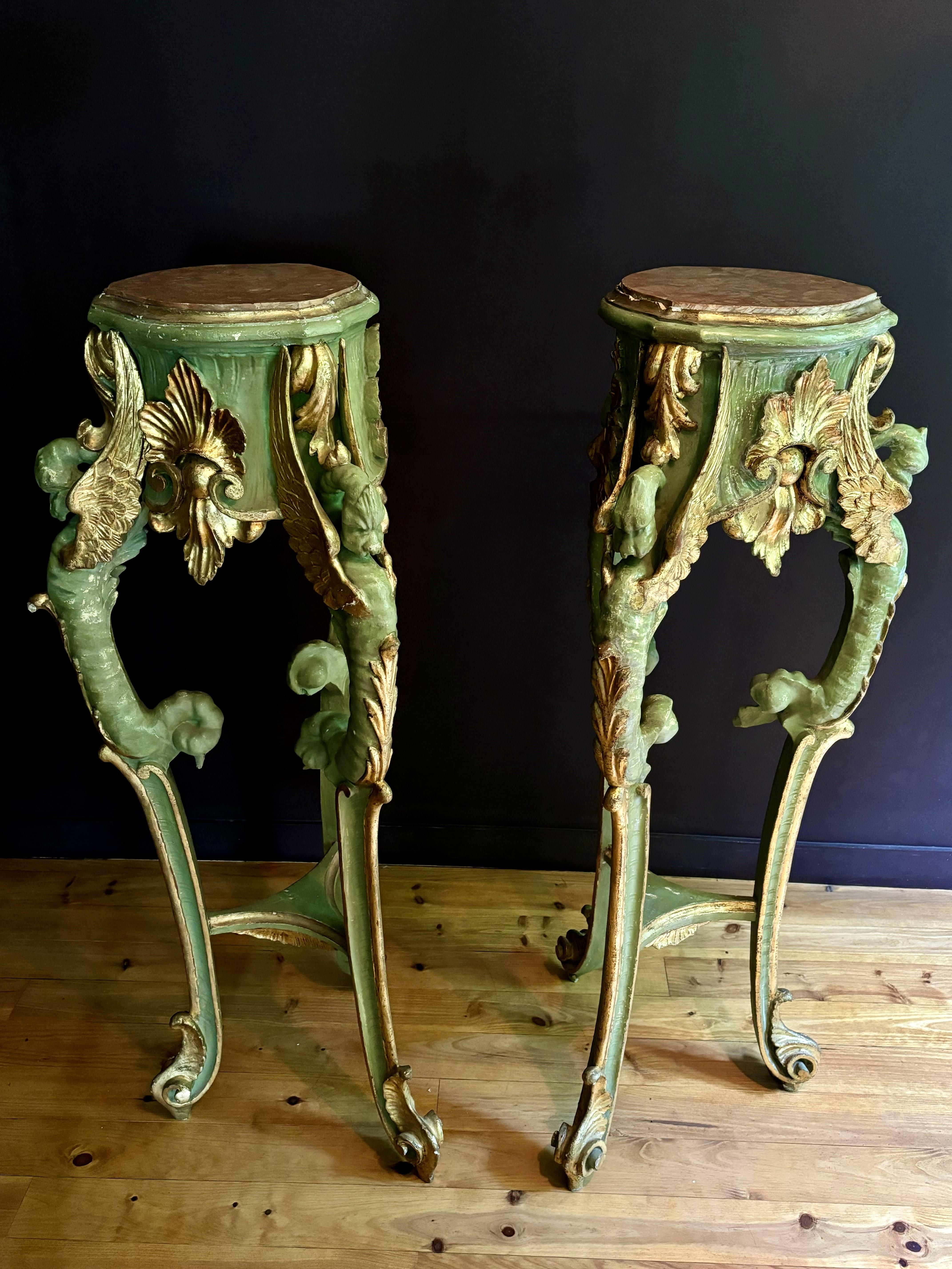 Espectacular y elegante pareja de pedestales de madera tallada, pintada y dorada. Cinturón decorado con hojas de acanto, encimera de mármol rojo sostenida por tres patas decoradas con dragones alados en la parte superior, unidas por un estante de