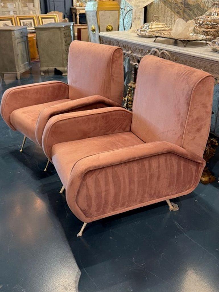 Le produit est une paire de fauteuils club italiens roses conçus d'après Marco Zanuso. Ces chaises présentent une couleur rose vibrante tapissée d'un tissu de velours et des pieds en laiton, ajoutant une touche d'élégance et de sophistication à