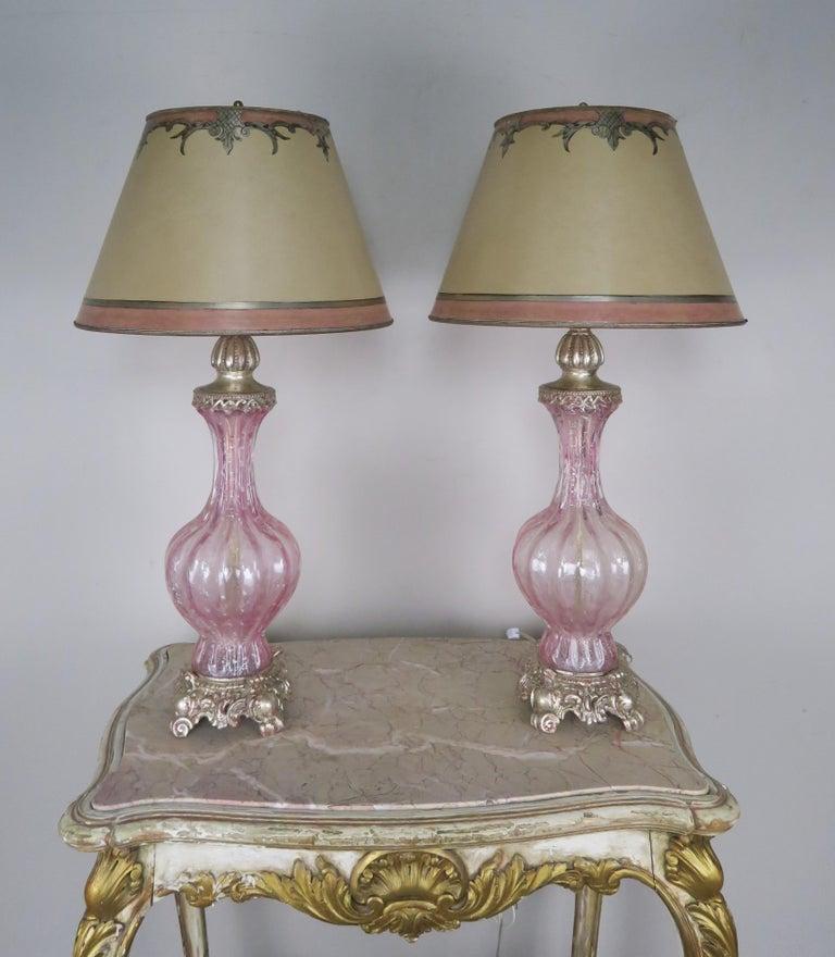 Paire de lampes italiennes en verre rose de Murano reposant sur des bases en métal argenté. Les teintes sont des parchemins peints à la main dans des couleurs coordonnées de rose et d'argent. Les lampes ont été récemment recâblées et sont en état de