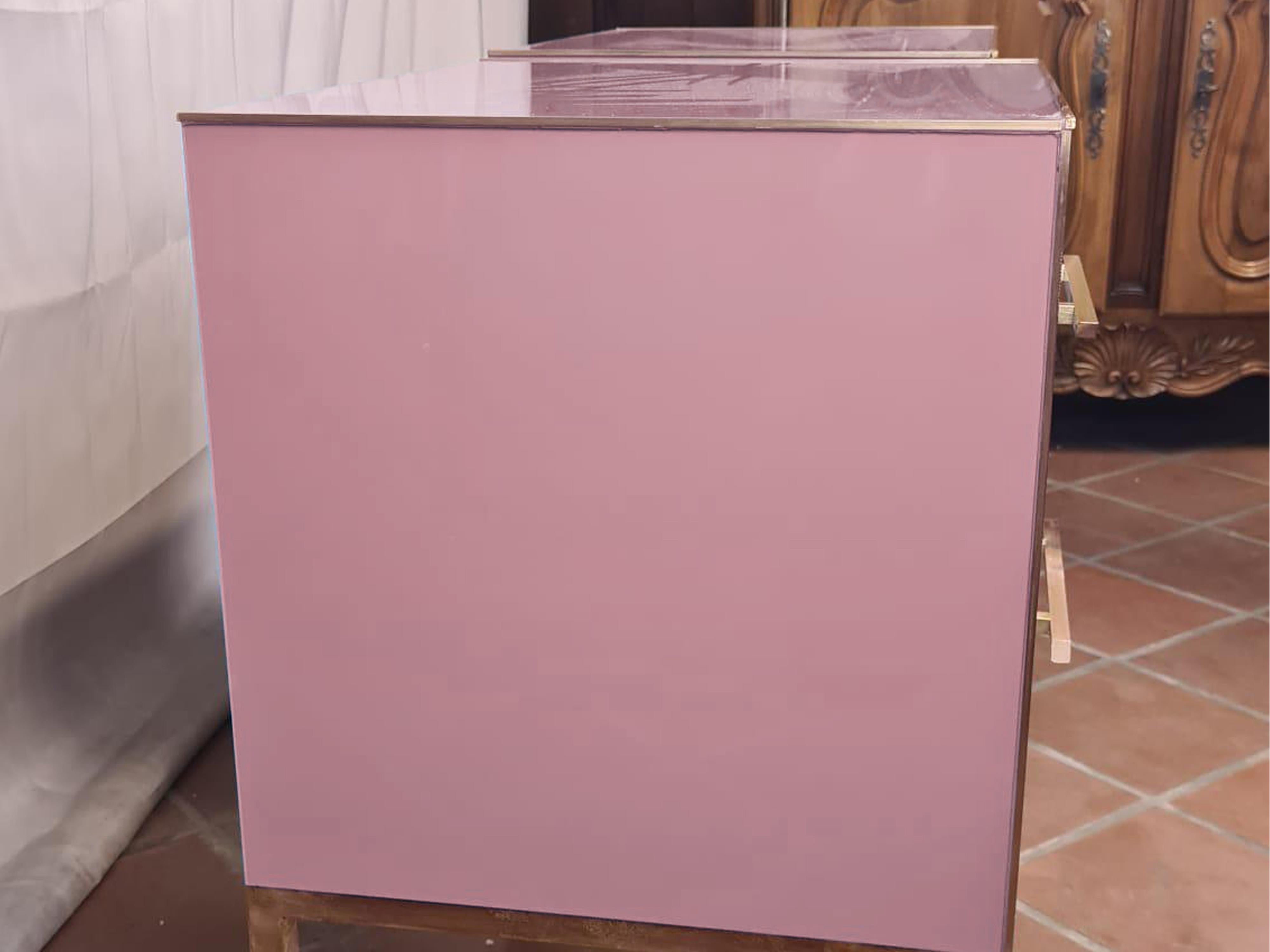 This refined pair of Italian bedside tables, first produced in 2022, showcases the elegance of pink Murano glass combined with intricate brass detailing and luxurious grey velvet upholstery. 

Made from high-quality birch, these bedside tables