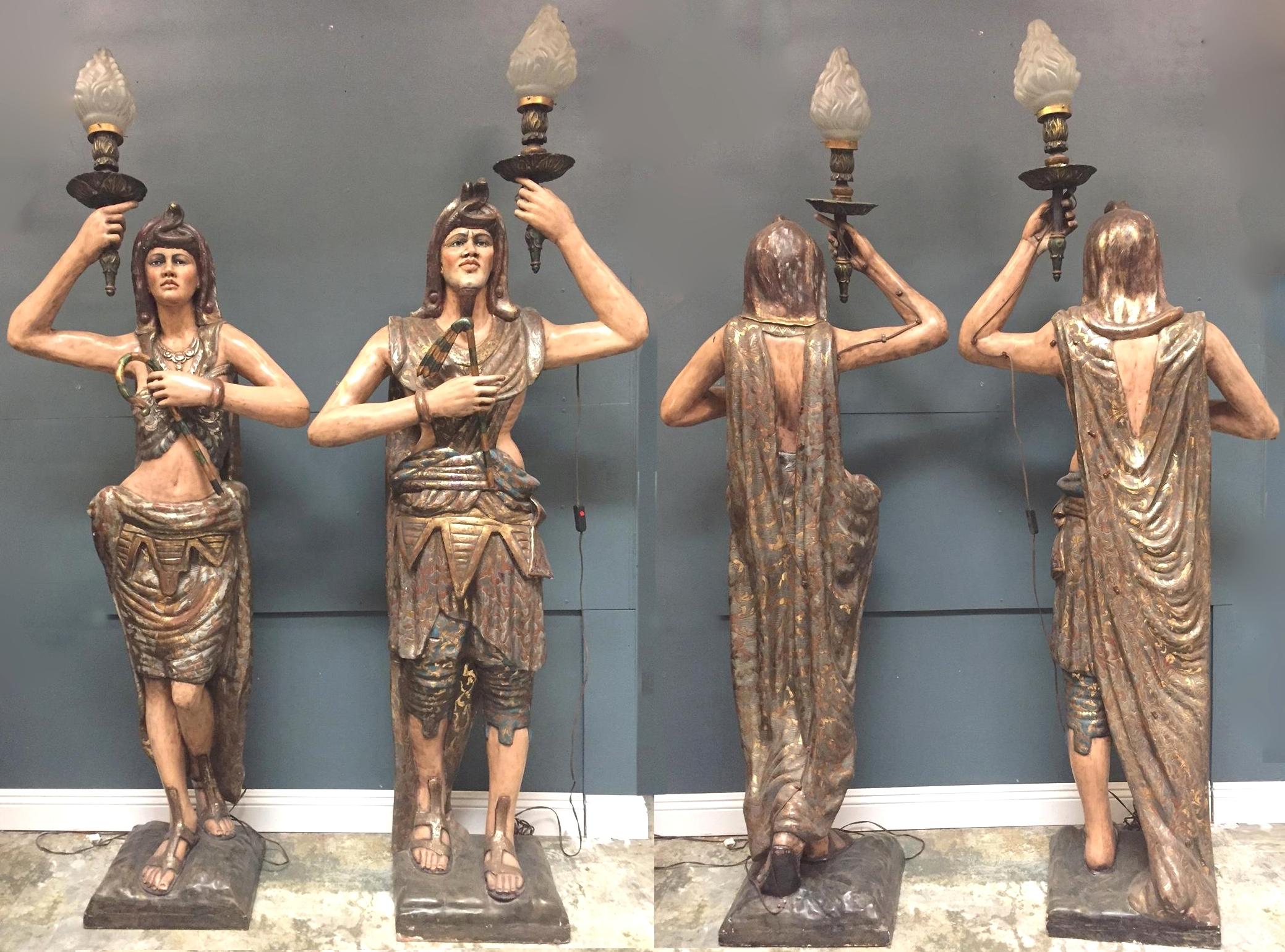 Impressionnante paire opposée de torches figuratives vénitiennes de style égyptien, polychromées et décorées à la peinture.
Début du 20e siècle.

Un homme et une femme nubiens grandeur nature, chacun vêtu de vêtements traditionnels polychromes de