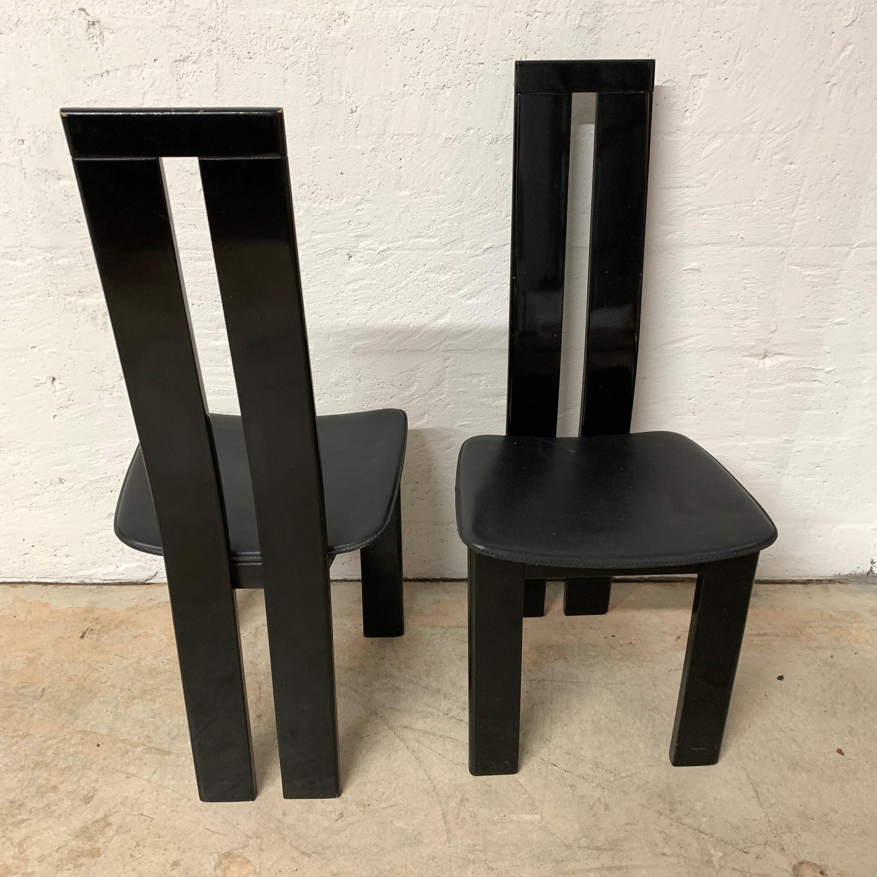 Set of two Postmodern chairs rendered in black lacquered wood frame with black stitched saddle leather seats, attributed to Massimo Vignelli.