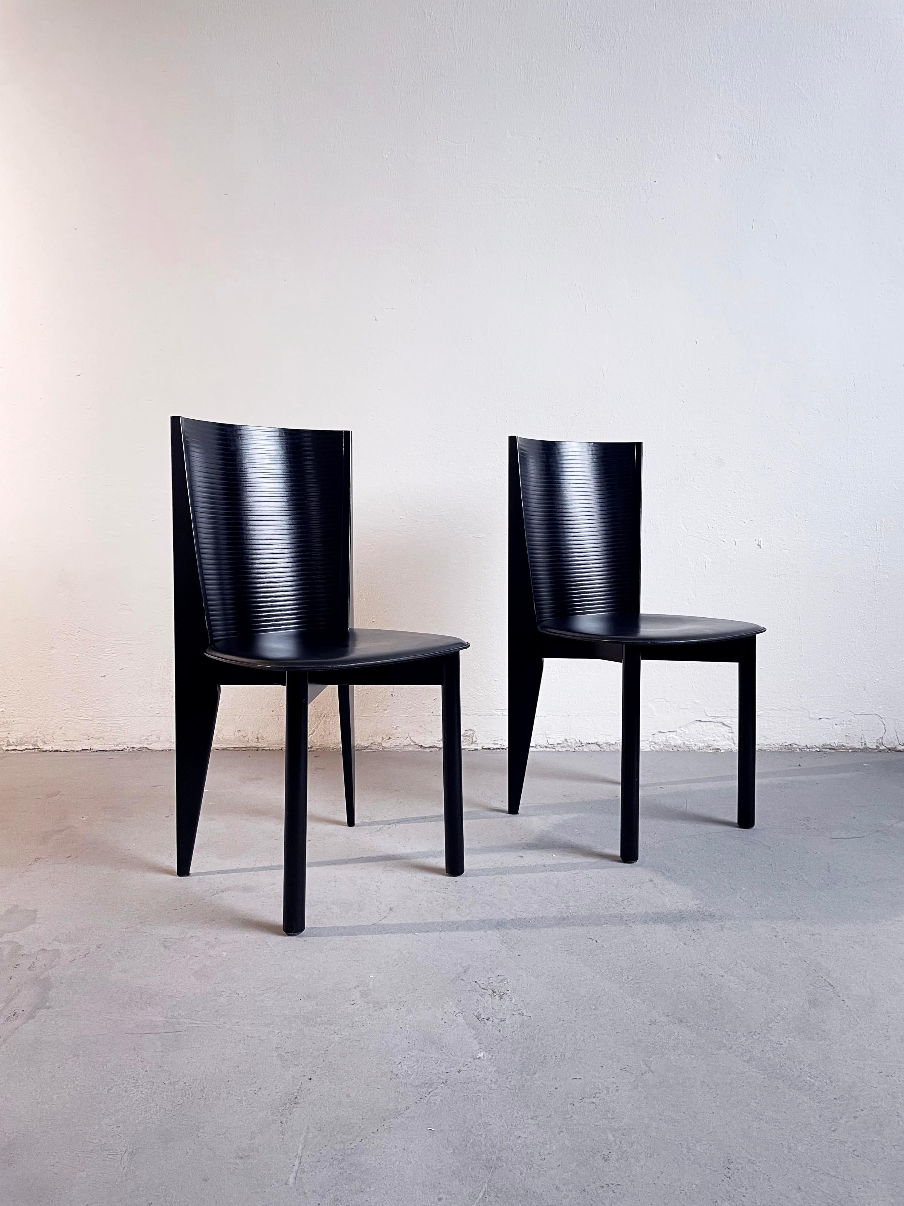 Pair of stunning postmodern Italian dining chairs produced by Calligaris in the 1980s
The chairs feature a black sculptural lacquered wooden frame and a black leather seat

Marked 'Calligaris' on bottom
Both chairs are in very good condition.