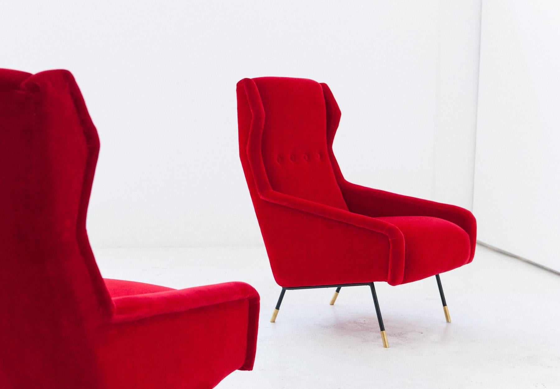 Set of two armchairs, designed and produced in Italy in  1950s.
These high back chairs has been reupholstered with new red velvet, also the padding is new.
These wingback easy chairs has a iron and brass frame, the design is a typical example of the