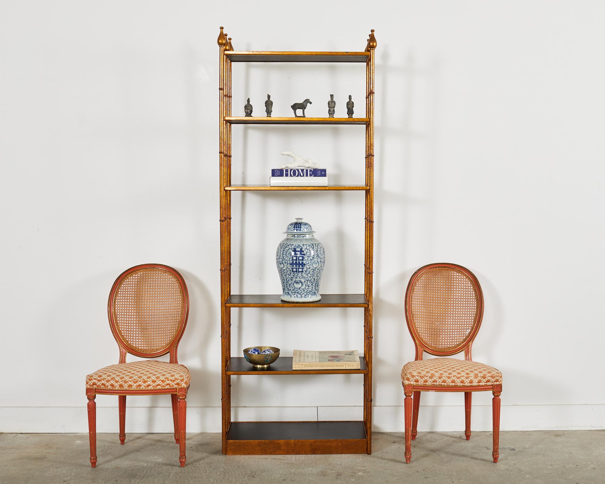 Stunning pair of matching midcentury Italian regency etagere display shelves or bookcases. The shelves feature a dramatic gilt finish on the iron faux bamboo frames inset with six black laminate ebonized wood shelves. The etageres are topped with