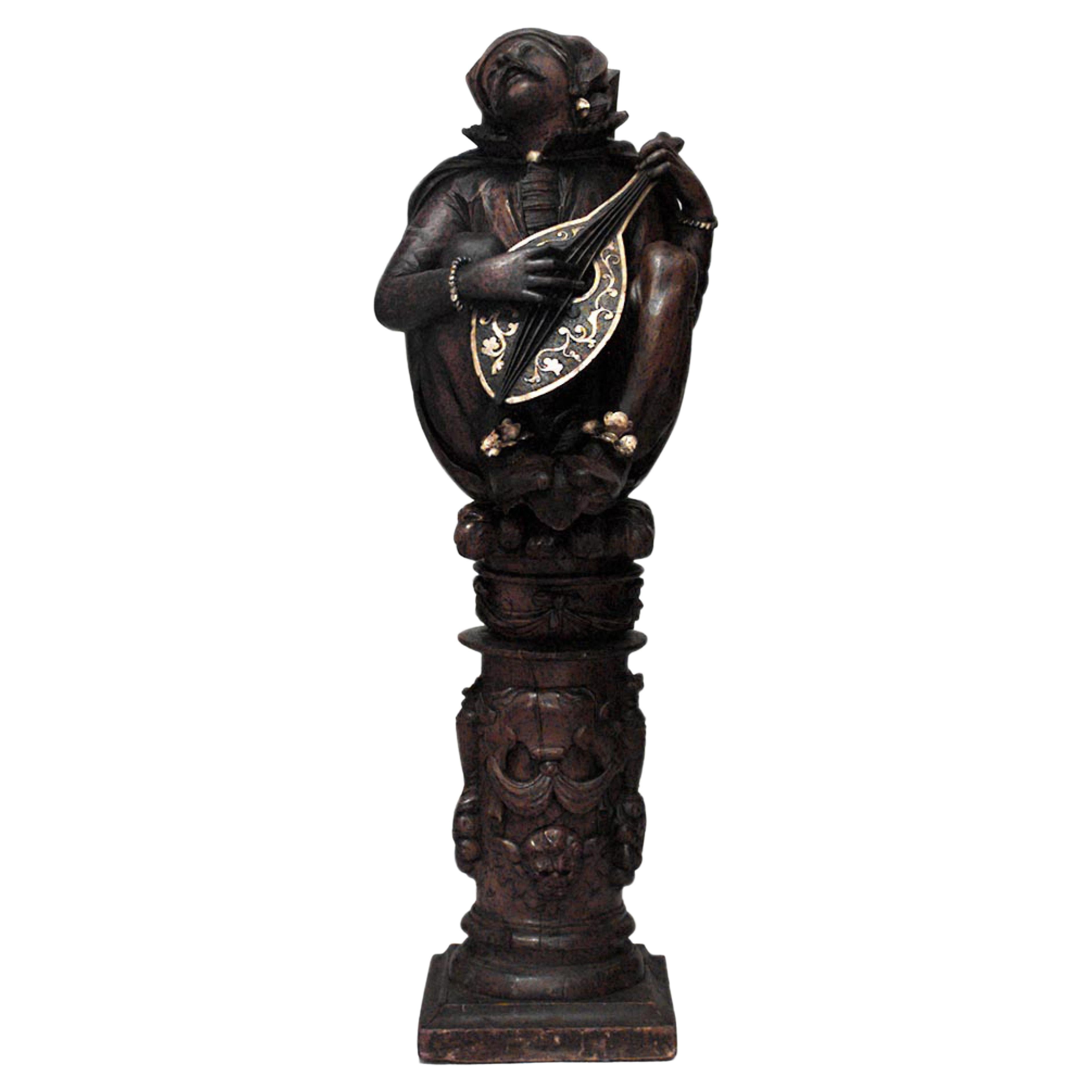Pareja de grandes figuras en cuclillas con instrumentos musicales, de estilo renacentista italiano (s. XVII-XVIII), en madera de nogal y adornos dorados, sobre peanas (PRECIO POR PAREJA).
 
