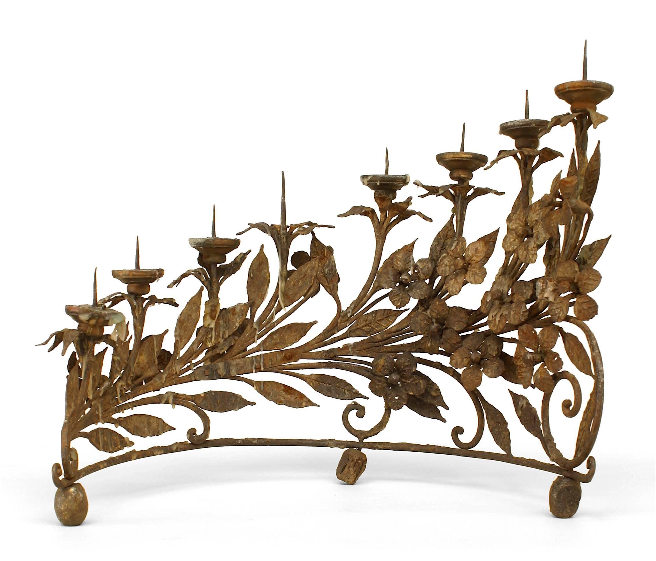 Pair of Italian Renaissance style (19th century) wrought iron eight-light candelabra in a half moon form with floral and leaf design and raised on three bun feet.
 