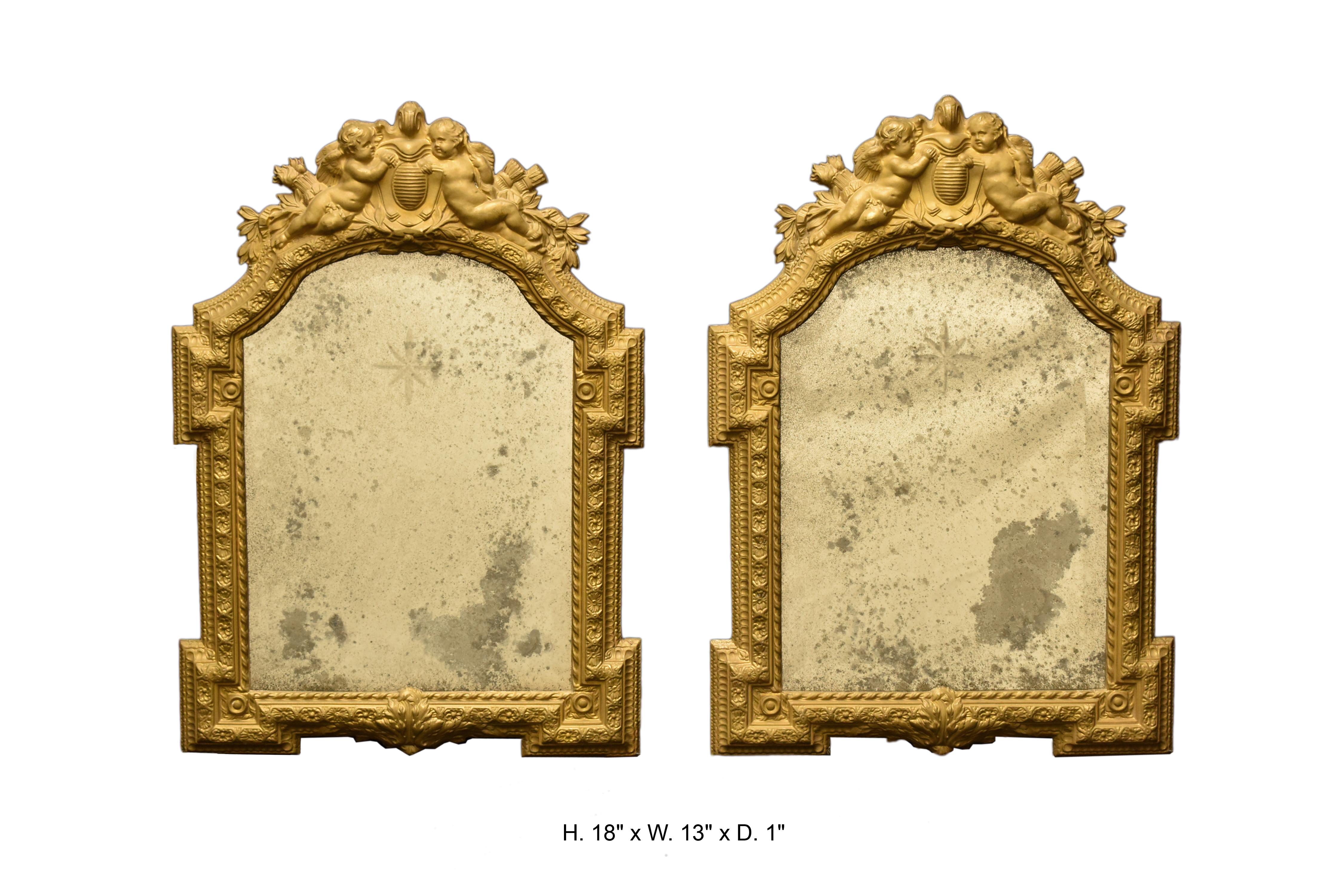 A beautiful pair of Italian repousse small mirrors, Mid 20th century 

Each mirror is surmounted with a cresting centered by a crest flanked with two finely crafted repousse brass cherubs amongst foliage, above an engraved shaped mirror plate in a
