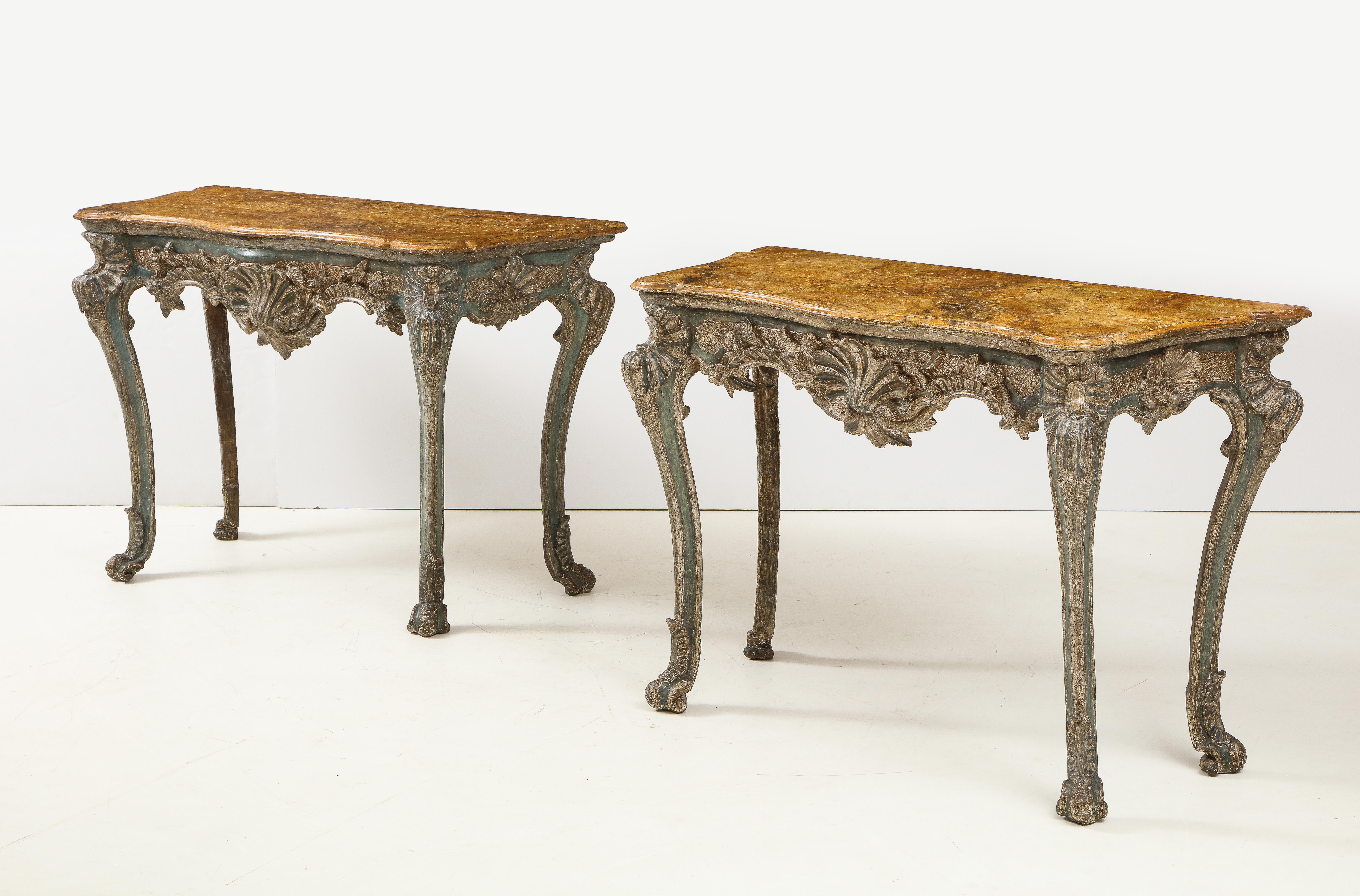 Fine pair of 18th century Italian rococo console tables, the faux painted wood tops imitating Sienna marble with scalloped sides and molded edge over foliate and rocaille carved frames in original blue paint and silver 