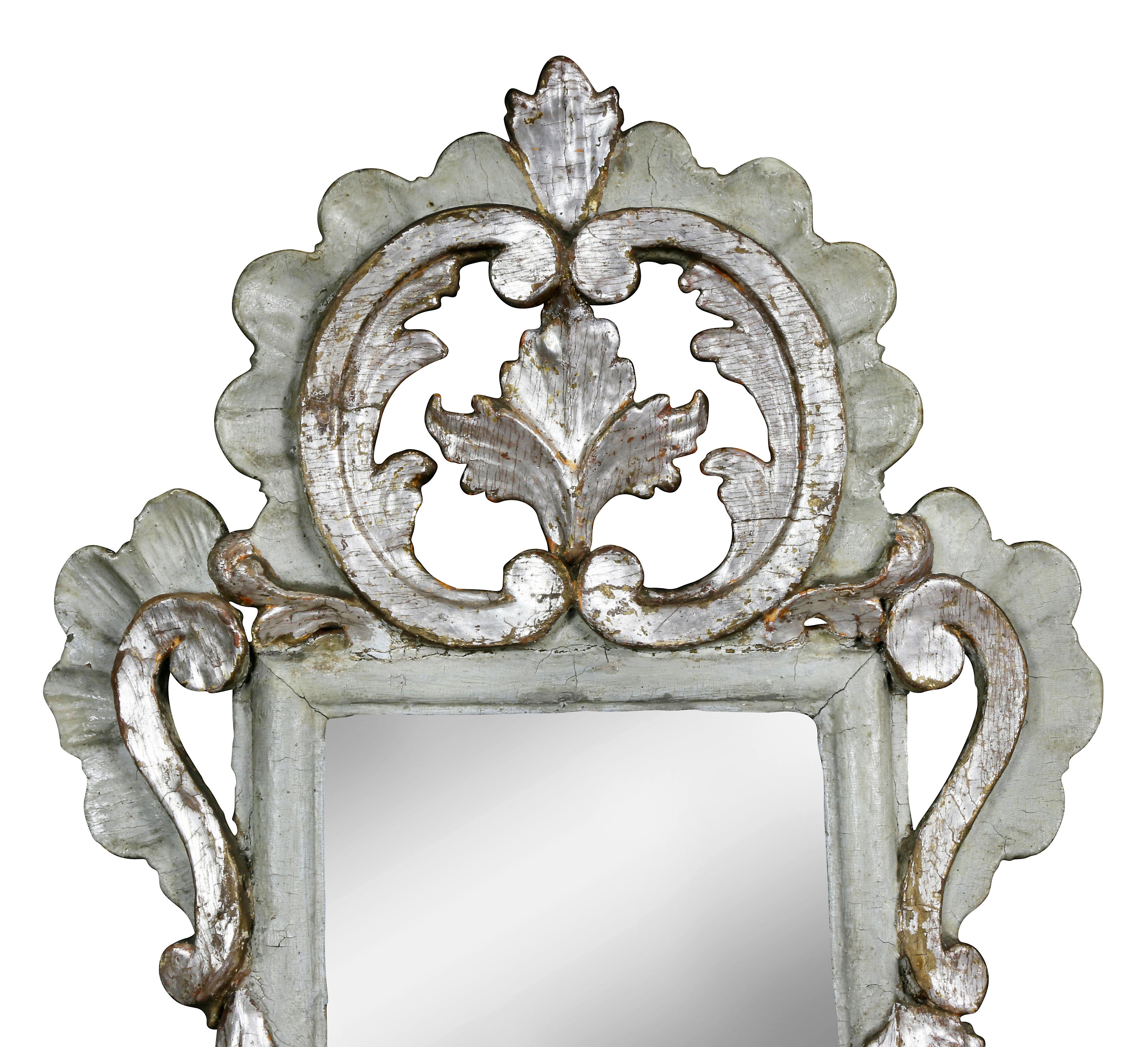 Each with a double scroll crest with central opening with leaf, over a mirror plate within a carved frame, similarly carved base with three candle arms. Provenance; Henry Forbes Bigelow, Boston architect. These are pictured in an article from The