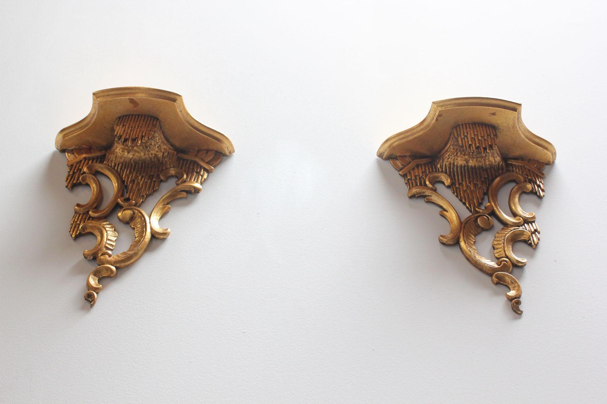 Pair of gilded Italian Rococo-style wall brackets (ca. 1950).
Deeply carved in high relief with rocaille c scroll accents and acanthus leaf decoration supporting shallow shelf surfaces. Each bracket has two hooks for hanging.
Minor gilt loss /