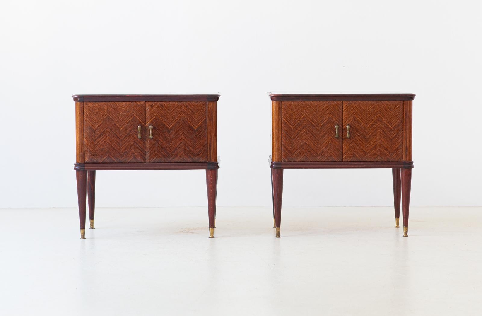 Set of two nightstands, manufactured in Italy during the 1950s
These two side tables has made of rosewood with grey/silver retrolacquered glass top. Brass handles and feets.
Handwork of herringbone doors. 

Very good shape, only light and