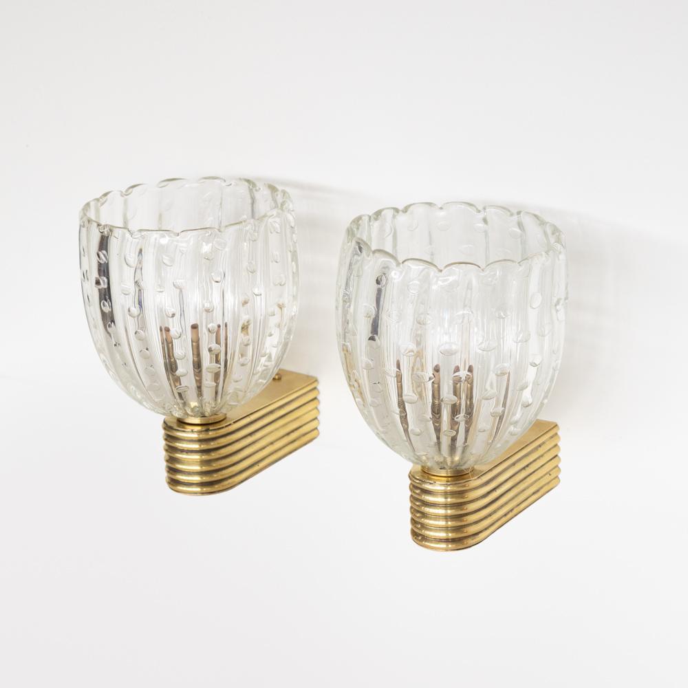 Wunderschönes Paar mundgeblasener Glasleuchten aus Italien, 1950er Jahre. Klare, gewellte, gerippte Glasschirme mit blasigen Details im Glas. Gerippter Messingarm mit schöner Alterung und Patina. Neu verdrahtet, Rückwand misst 1,75