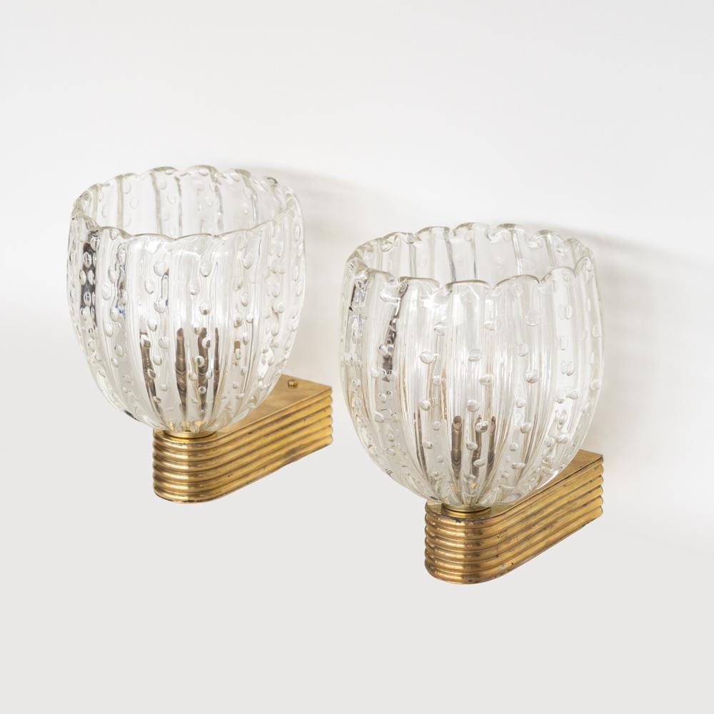 Stunning pair of blown glass sconces from Italy, 1950's. Clear scalloped ribbed glass shades with bubbled detail within glass. Ribbed brass arm with nice age and patina. Newly wired, backplate measures 1.75