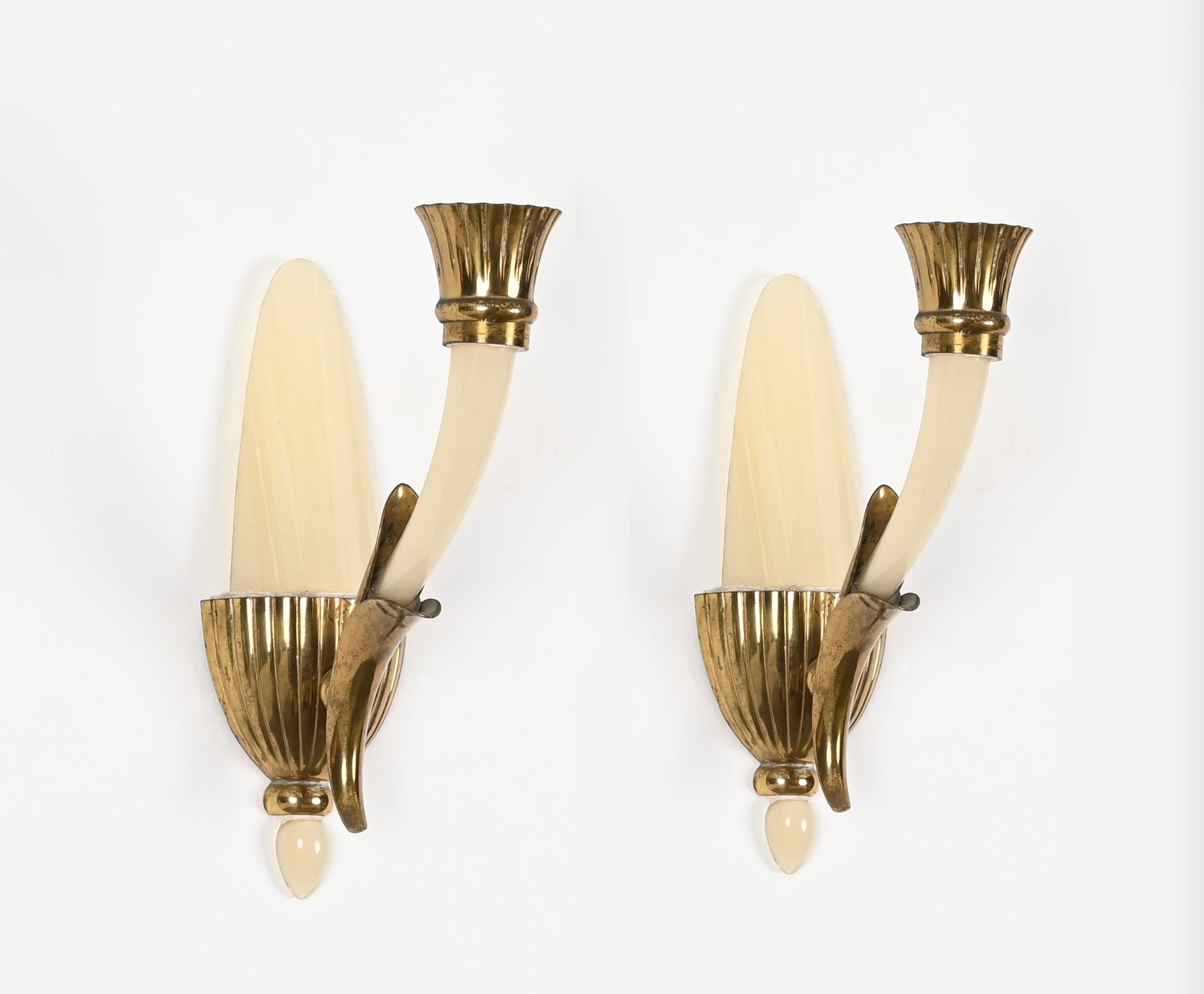 Wunderschönes Paar Wandlampen aus elfenbeinfarbenem Murano-Kunstglas und Messing. Diese charmanten Wandleuchter wurden von Guglielmo Ulrich entworfen und in den 1940er Jahren in Venedig hergestellt. 

Die Qualität dieser seltenen Wandleuchten ist