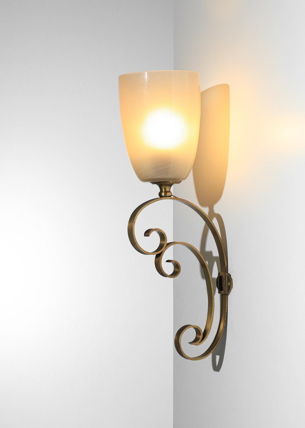 Paire d'appliques murales italiennes des années 60 attribuées à Massimo Vignelli. Structure en laiton massif et abat-jour en verre épais strié de Murano. Base très décorative avec des volutes en laiton. Très bel état vintage, avec des traces d'âge