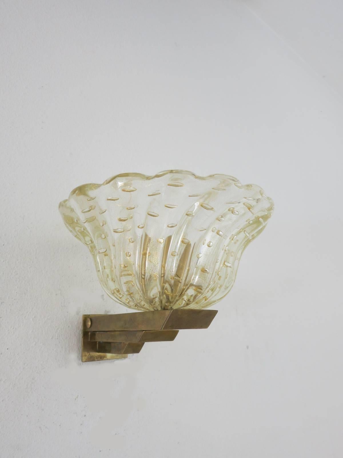 Vintage pair of Italian sconces with clear Murano glass infused with gold flecks and hand blown with bubbles within the glass in Pulegoso technique, mounted on brass bracket / Designed by Barovier e Toso, circa 1930s / Made in Italy.