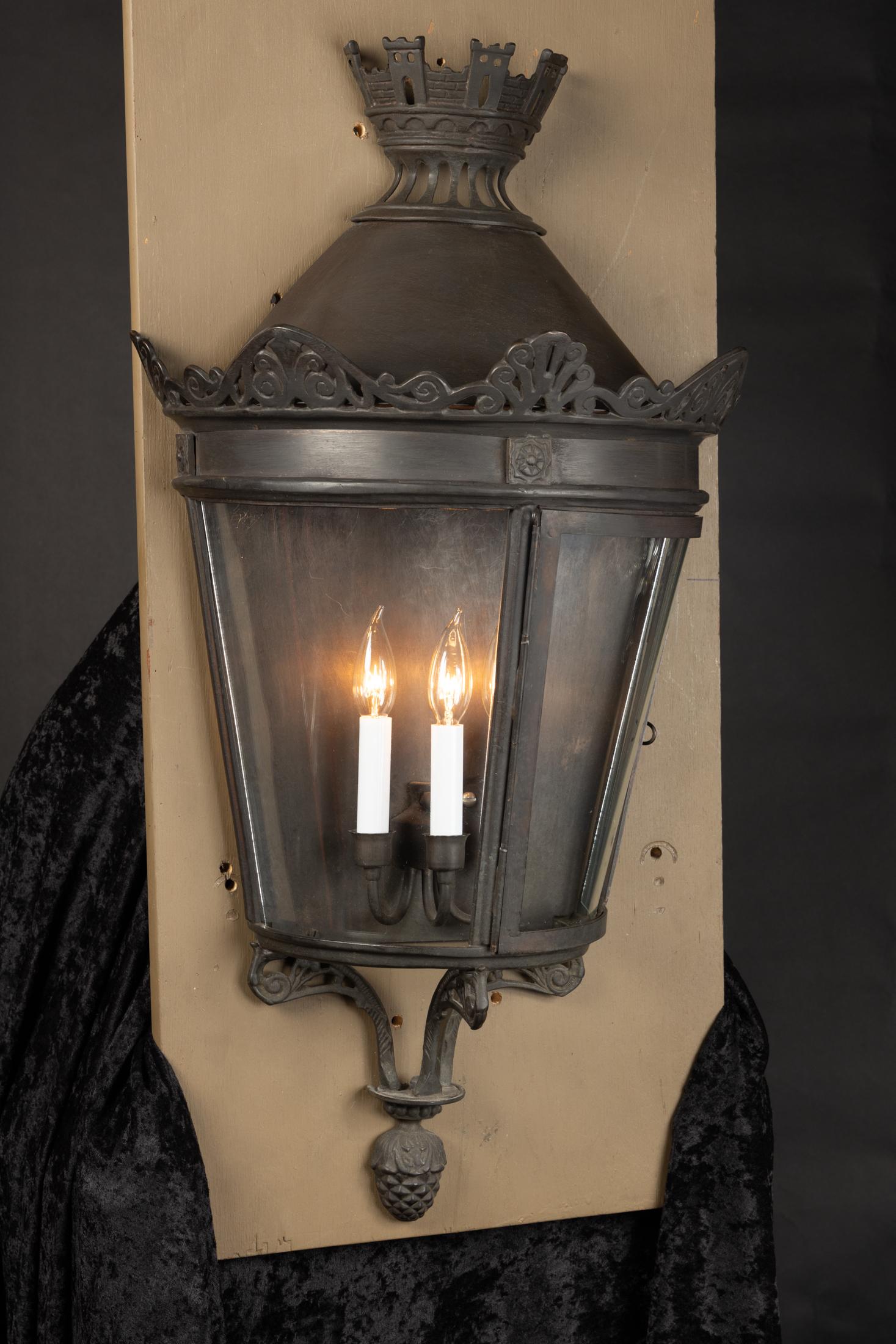 This beautiful pair of Italian semi-circular oscuro (dark) bronze wall lanterns features curved glass panes and made to resemble Parisian street lights of the 19th Century. The pair dates back to the 1950s and features a crown of castles at
