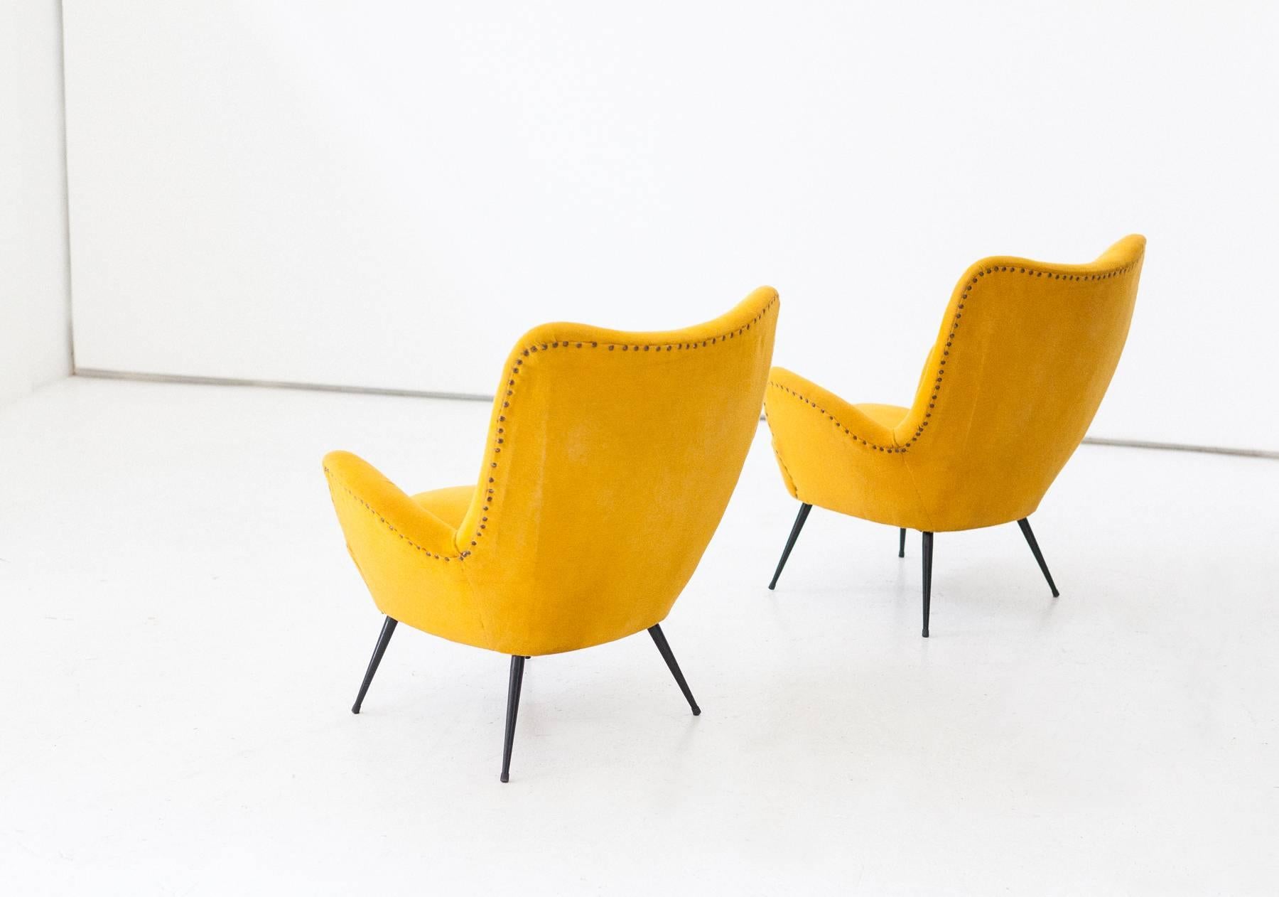 Set of two lounge chairs, designed and produced in Italy in the 1950s.
Senape yellow fabric, this was changed approximatively 10 years ago, cleaned and in good conditions. 
The chair has Iron legs with new black lacquer. this type of armchair