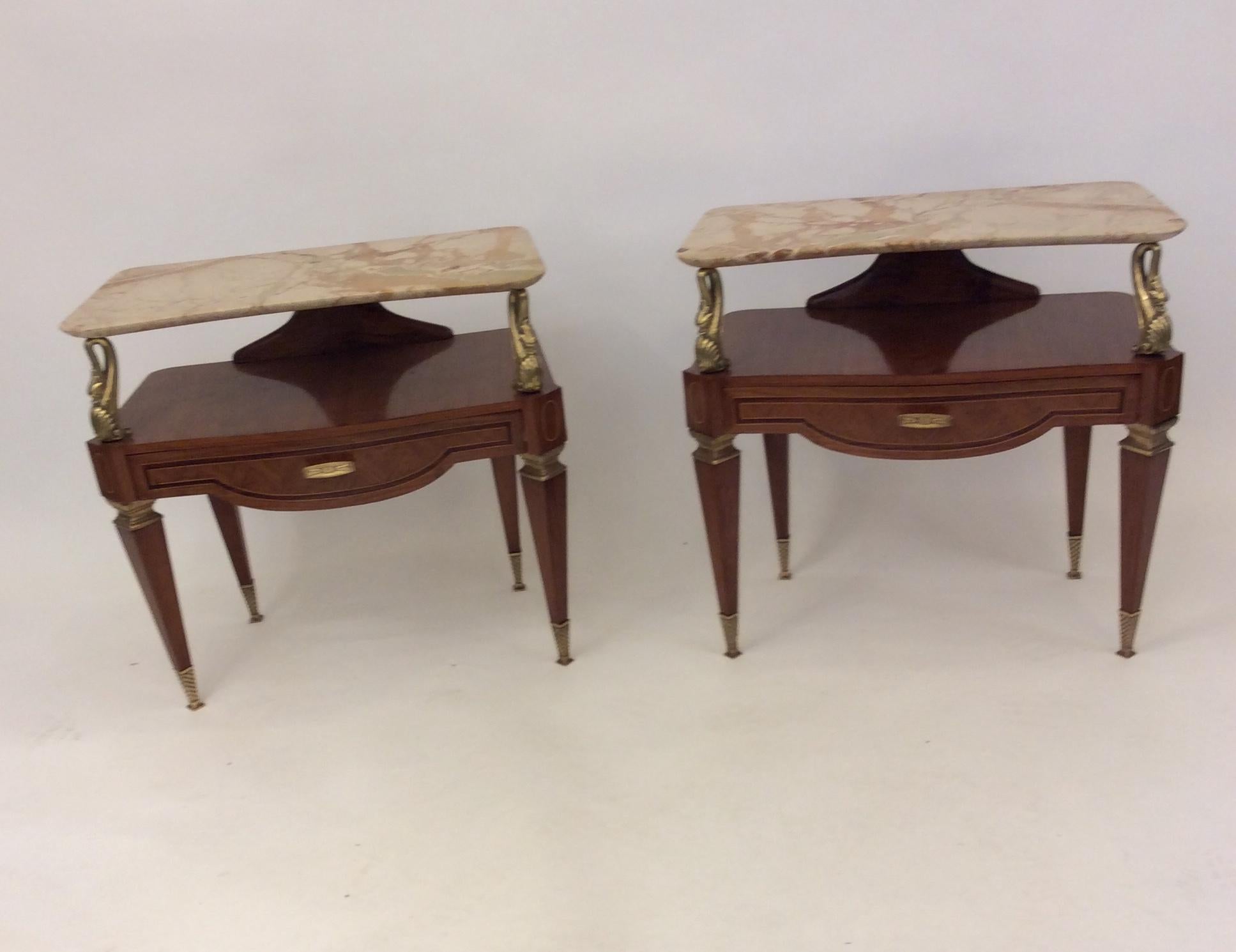 An amazing pair of Italian side tables or nightstands. A mix of woods, tapered legs leading to brass shoes. Decorative brass swans supporting a beautiful marble shelf. Each table has a drawer with brass hardware. 
Attributed to Gio Ponti, circa 1940.