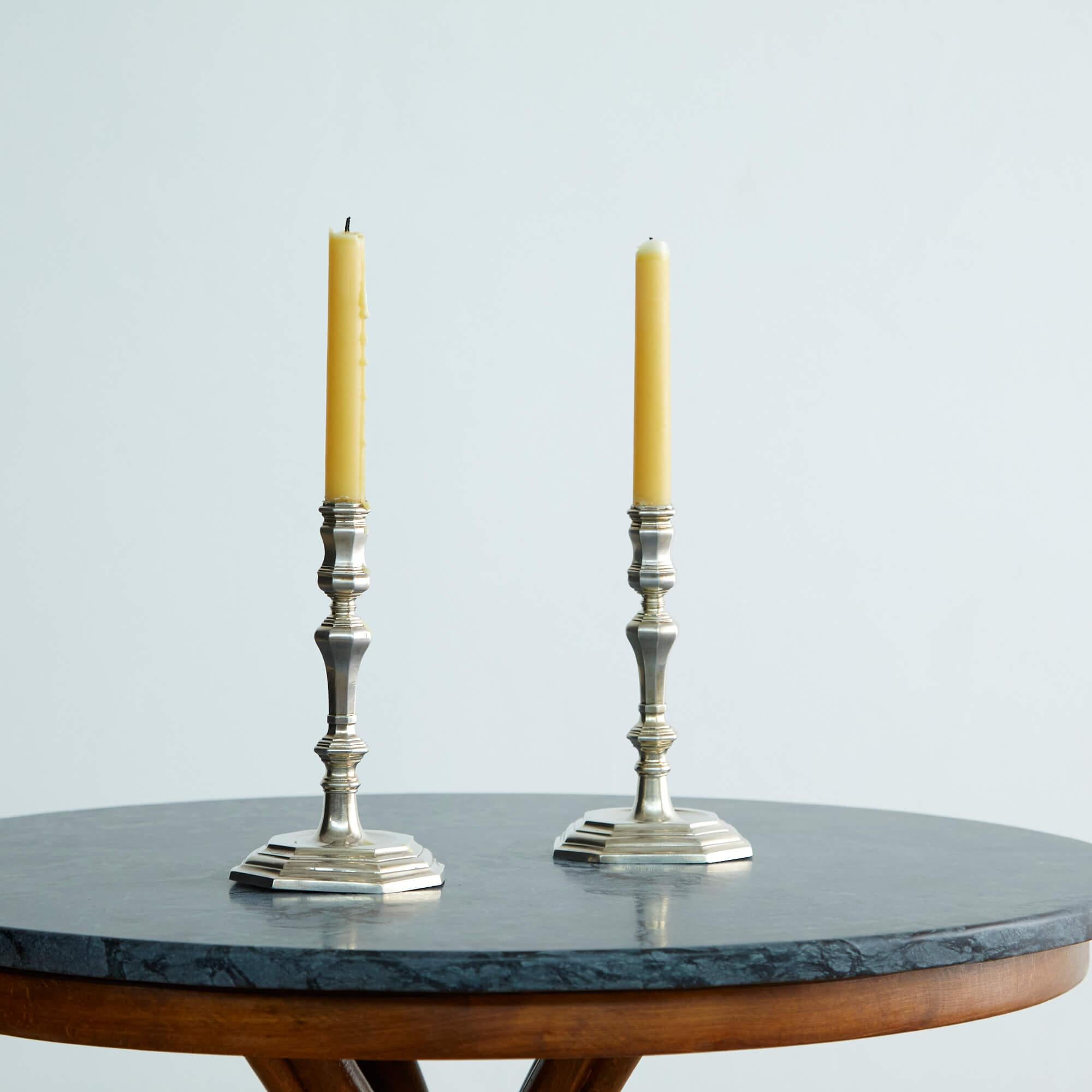 These mid-18th century Italian silver candlesticks bear a coat-of-arms engraved at the base, with a ducal cornet and symbols of a watchtower and bird in flight, suggesting their origin in the Papal States–or what is now the central Italian region