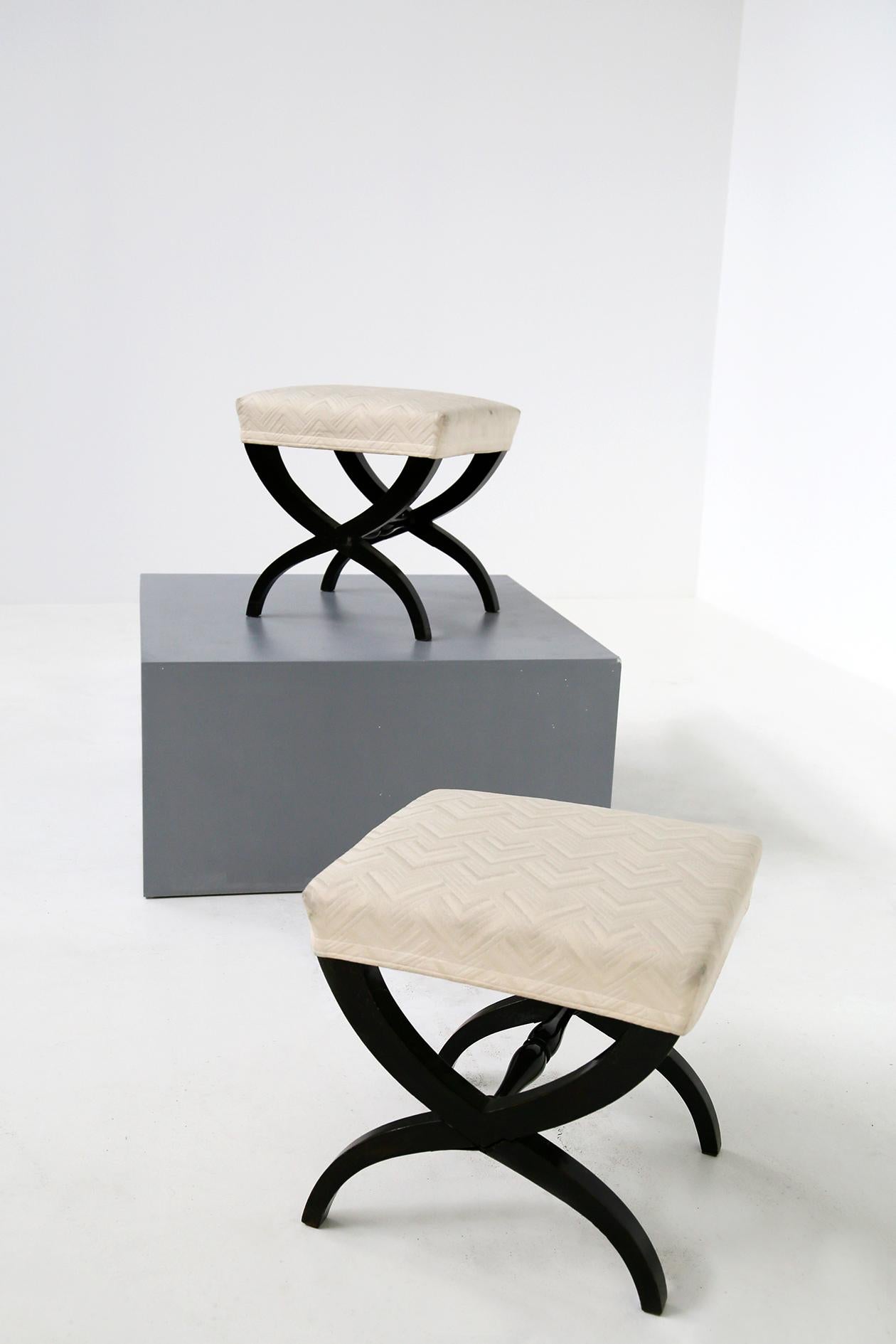 Elegant pair of midcentury stools of excellent workmanship. The pair of poufs are made of wood and its peculiarity are its black varnished wooden horn. The pouf has as seat an elegant cotton fabric with an elegant designed texture. The fabric is