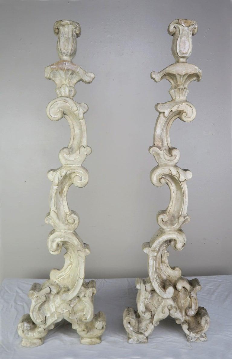 Pair of Italian style painted scrolled carved wood candlesticks. The candlesticks are comprised of scrolled acanthus leaves combined with carved tulip shaped tops.