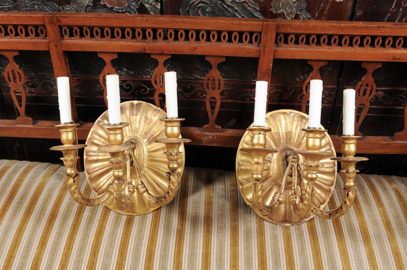 The pair of giltwood scones with oval carved sunburst backplate with 3 arms and wax candle sleeves. The sconces recently electrified for U.S.A electricity.

 